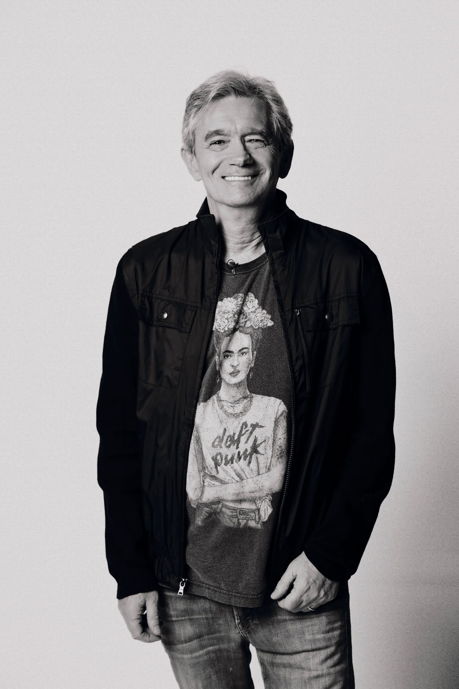 Black and white portrait of a person wearing a casual denim jacket and t-shirt against a light background.