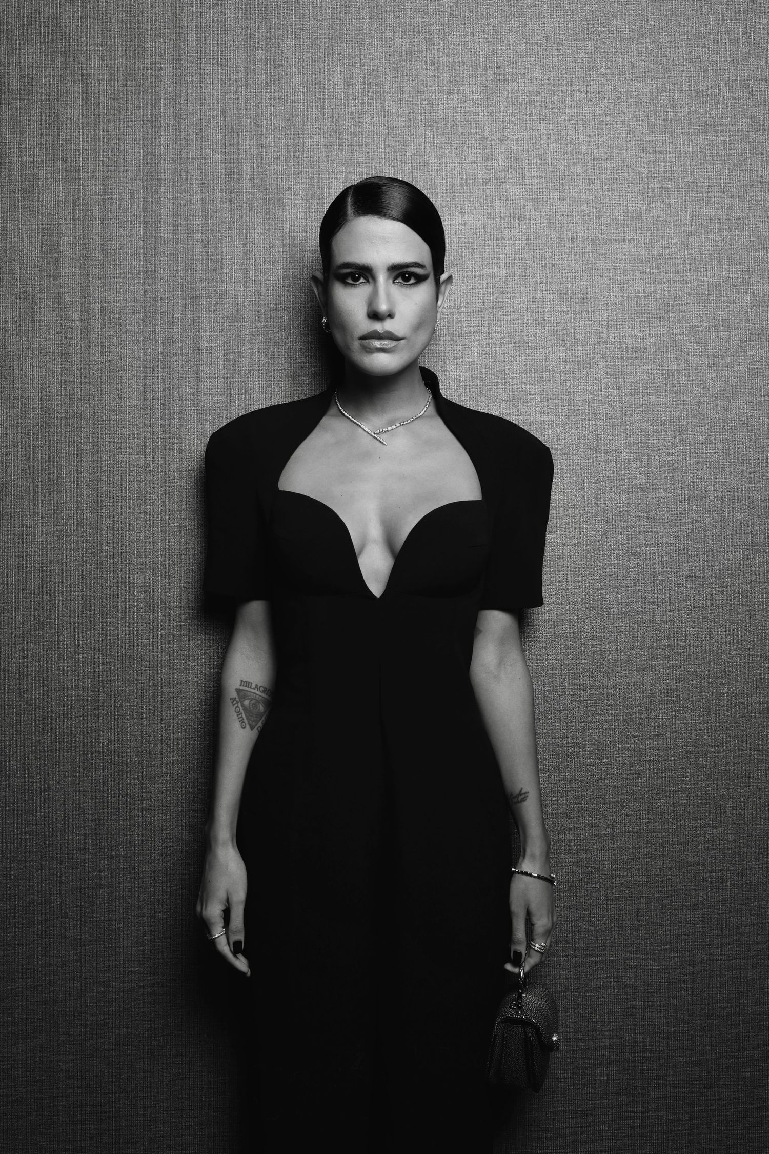 Black and white fashion portrait of person in elegant black dress against textured background.