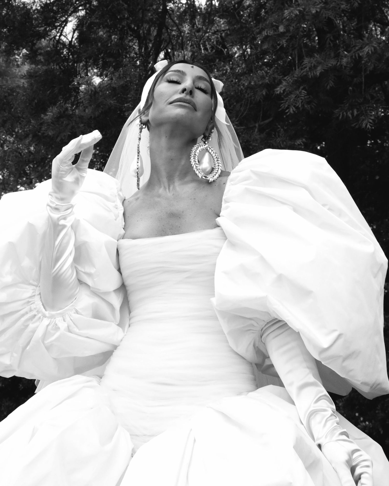 Artistic black and white bridal portrait featuring dramatic puff sleeve wedding dress and statement earrings.