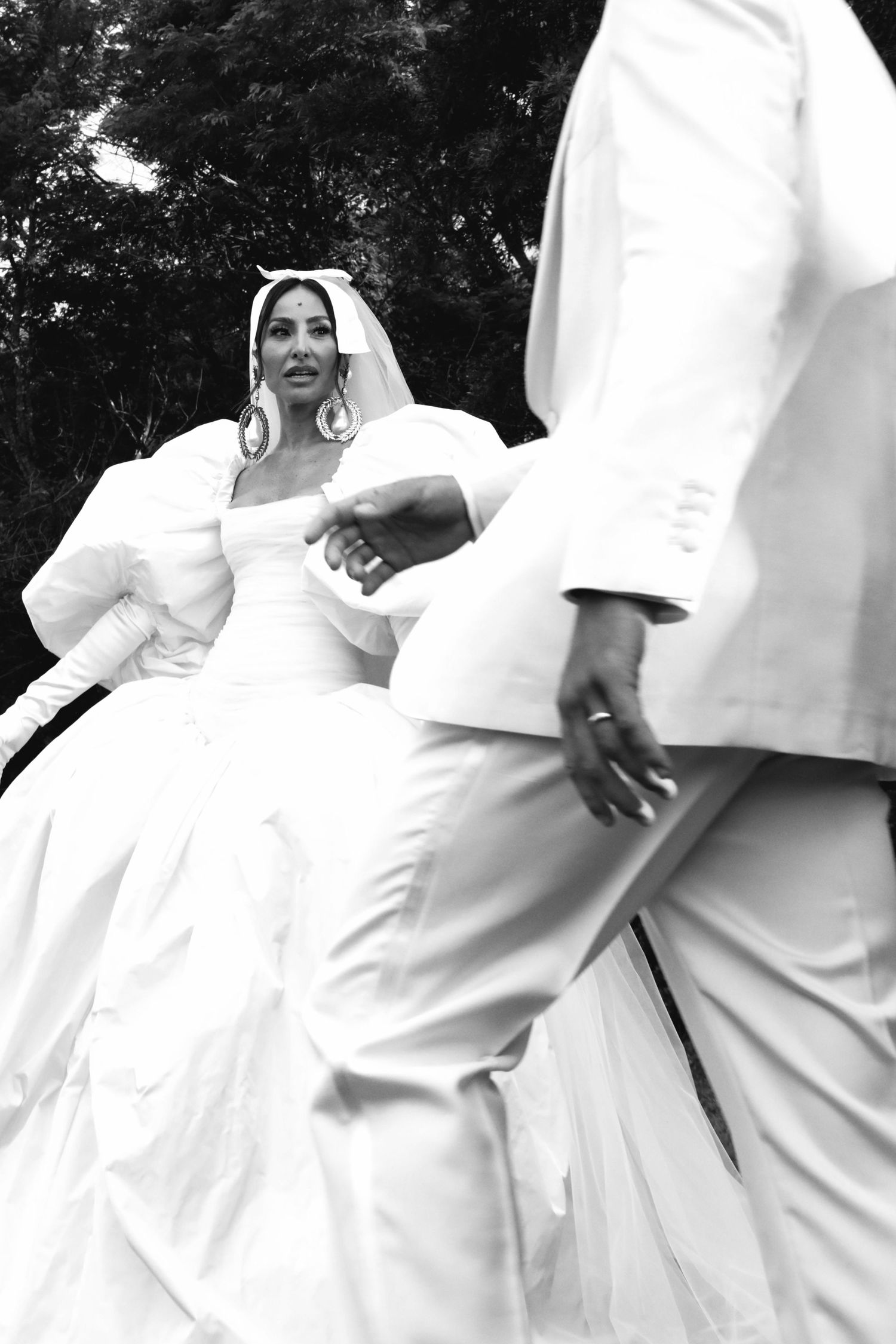 Black and white photo of wedding couple in all-white attire showing dress details and intimate moment.