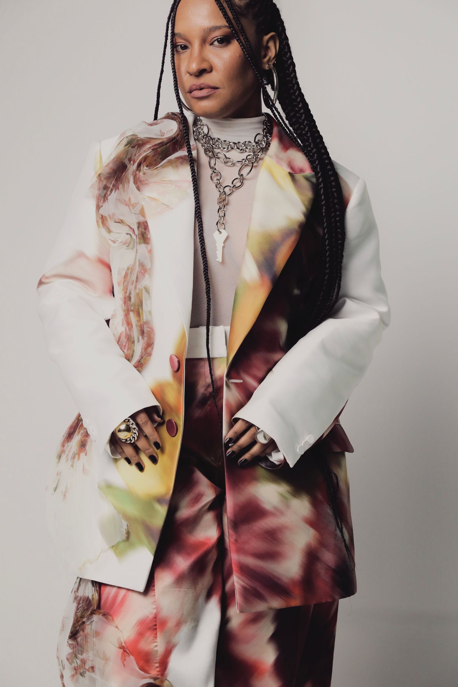 Fashion portrait featuring model in tie-dye blazer with statement necklace and braided hair.