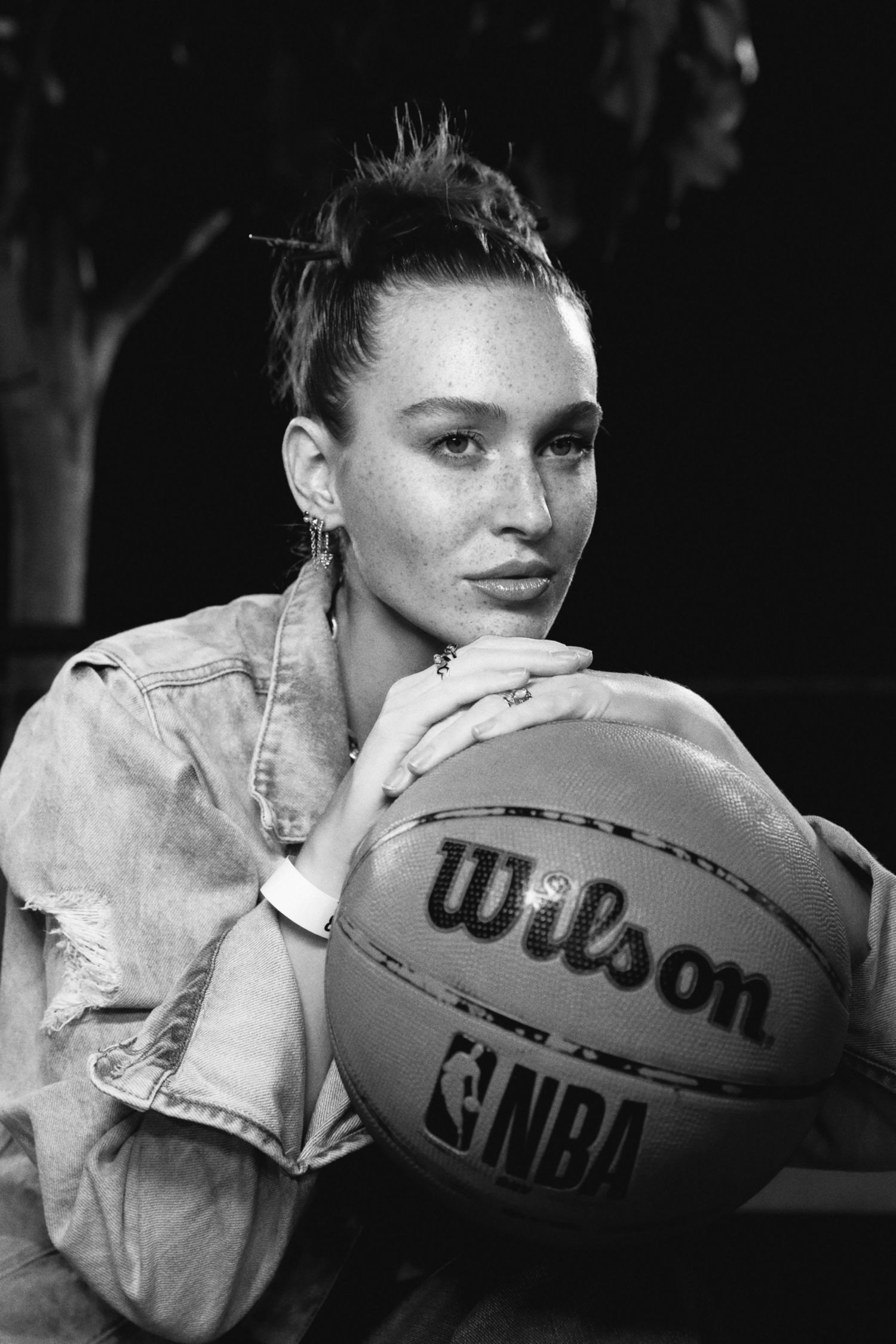 A casual portrait with a person holding a Wilson NBA basketball while wearing a denim jacket.