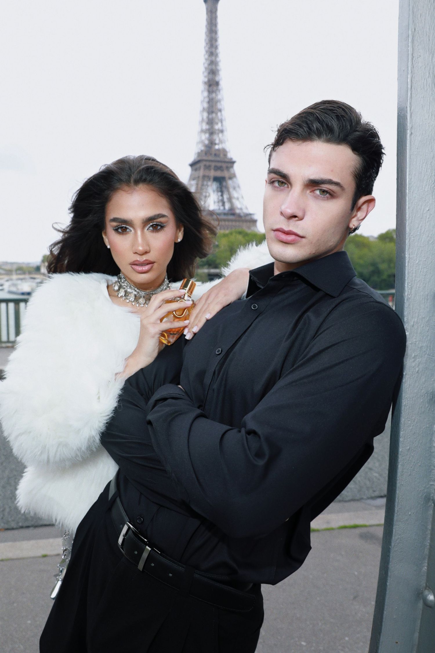Stylish couple poses in black and white outfits with Eiffel Tower backdrop in Paris.