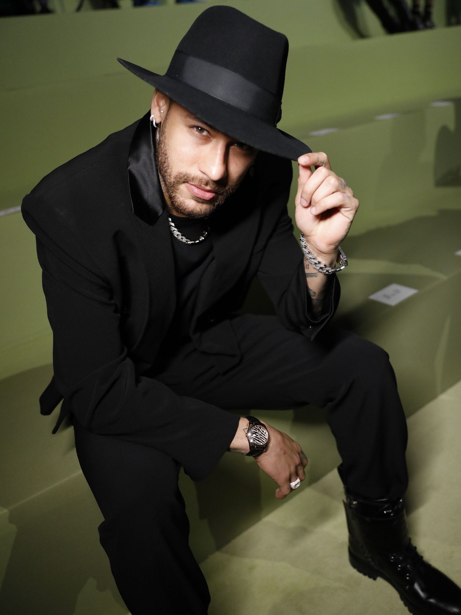 Stylish portrait of someone in all black with a fedora and jewelry.