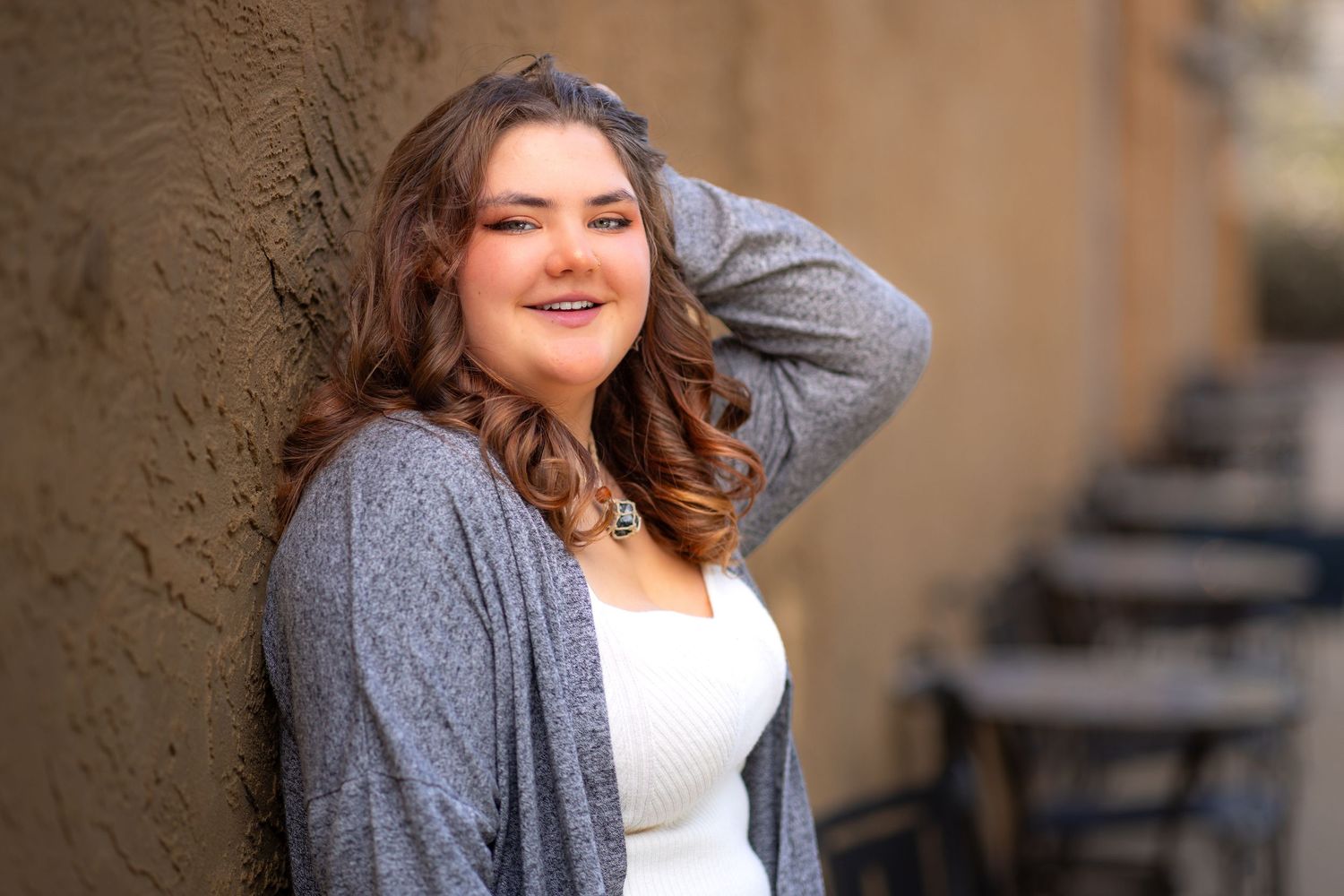 A girl leaning against a wall with a hand on top of head