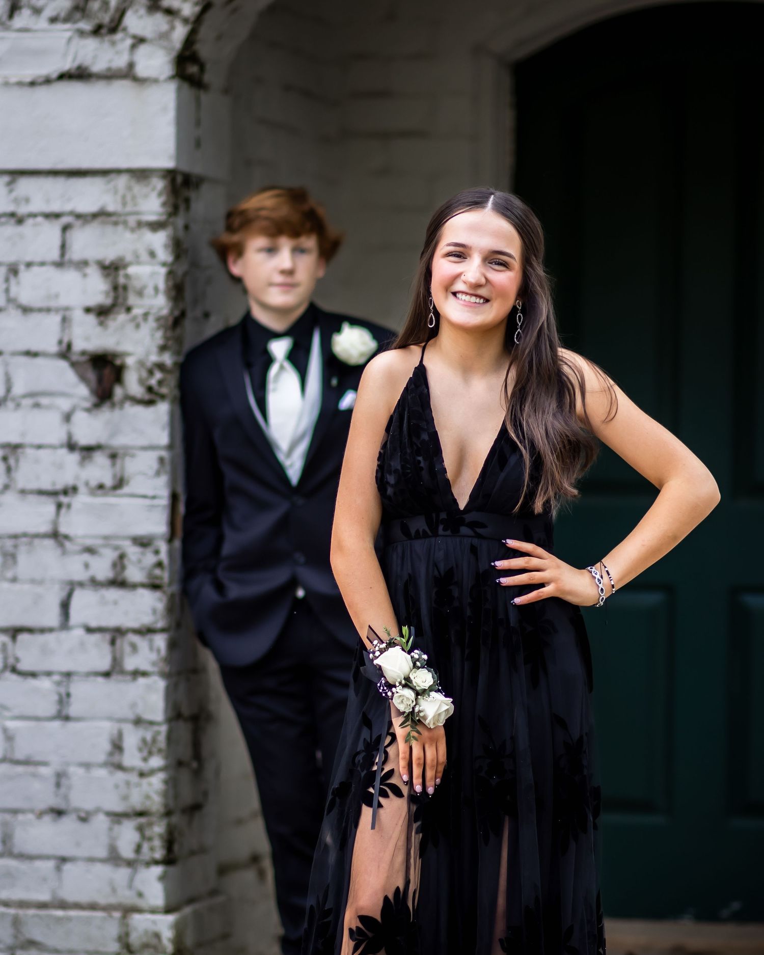 A prom photo with the boy behind the girl out of focus with his gaze cast upon the girl who is totally in focus
