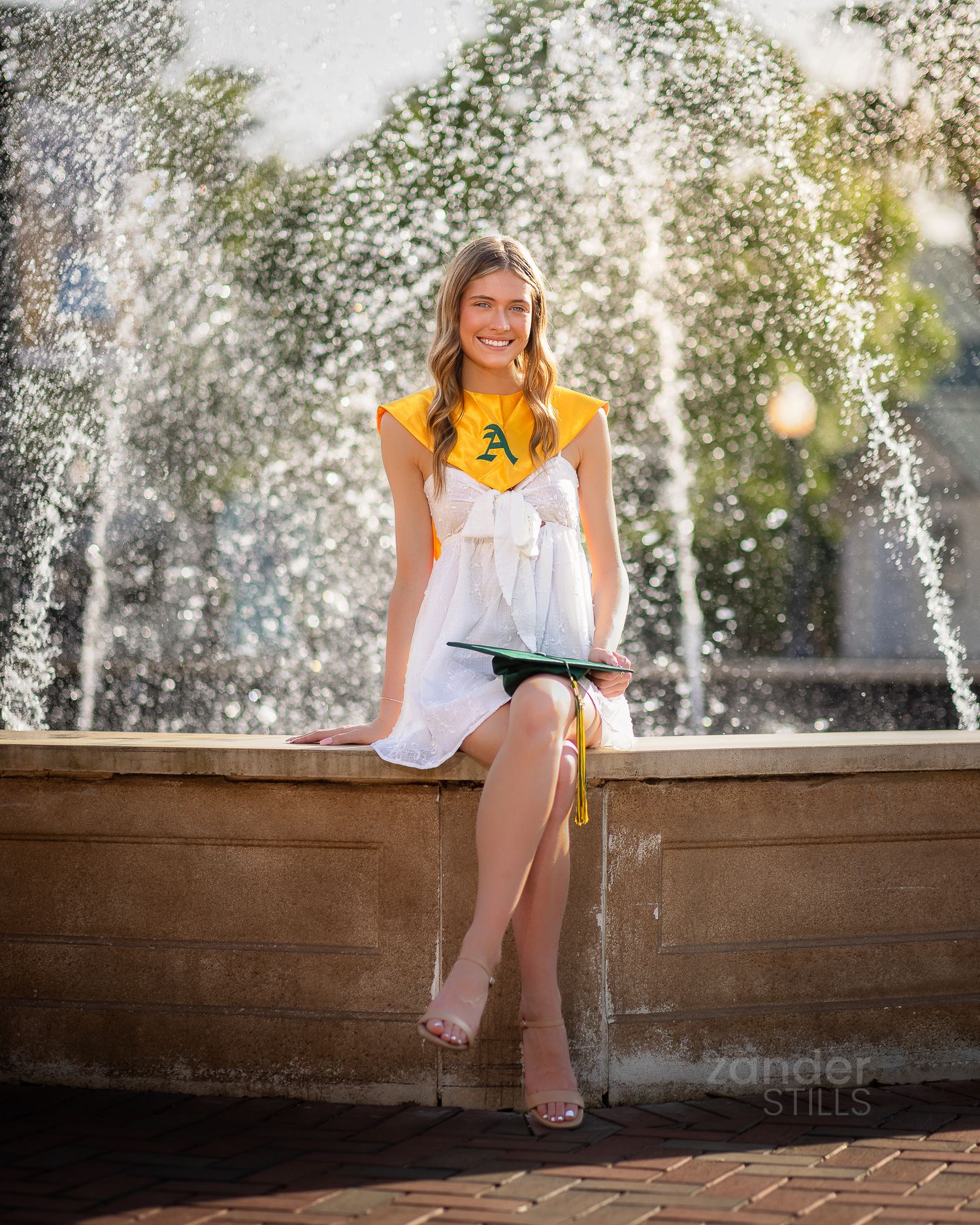 A high school senior sitting in front of a fountain