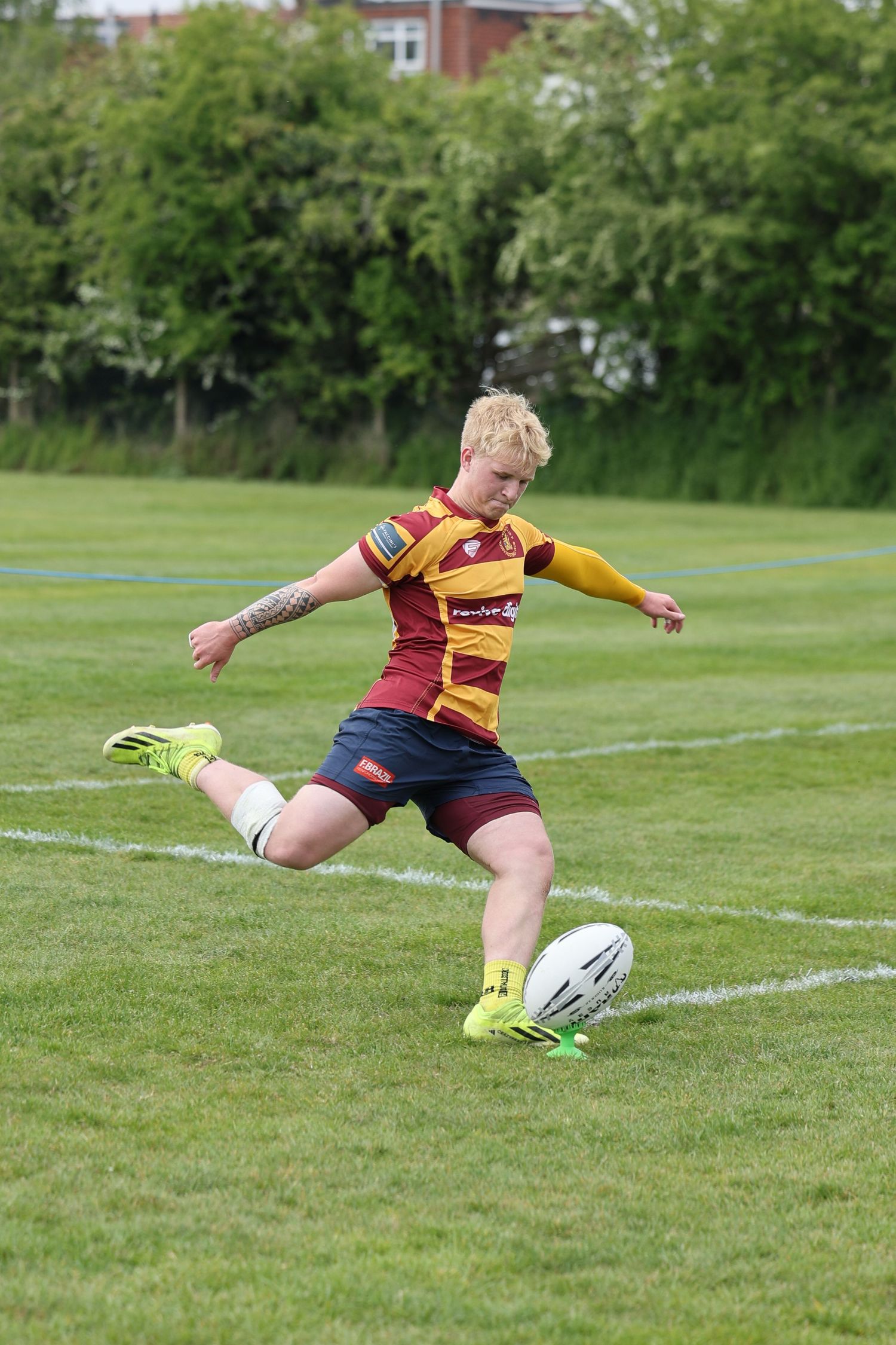 man kicking the rugby ball with his leg bent back.
