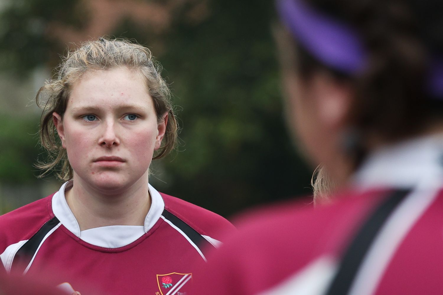 Over the shoulder shot of a female rugby player listenin to a team talk by the coach.
