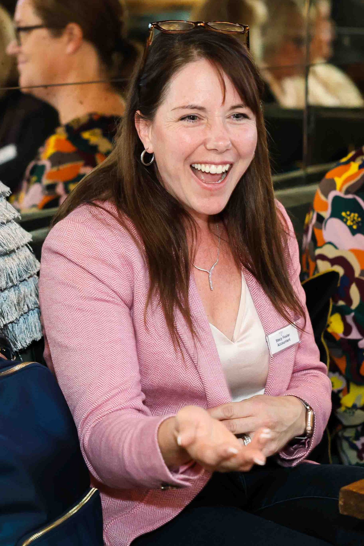 Woman in a pink jacket pointing and laughing at the camera