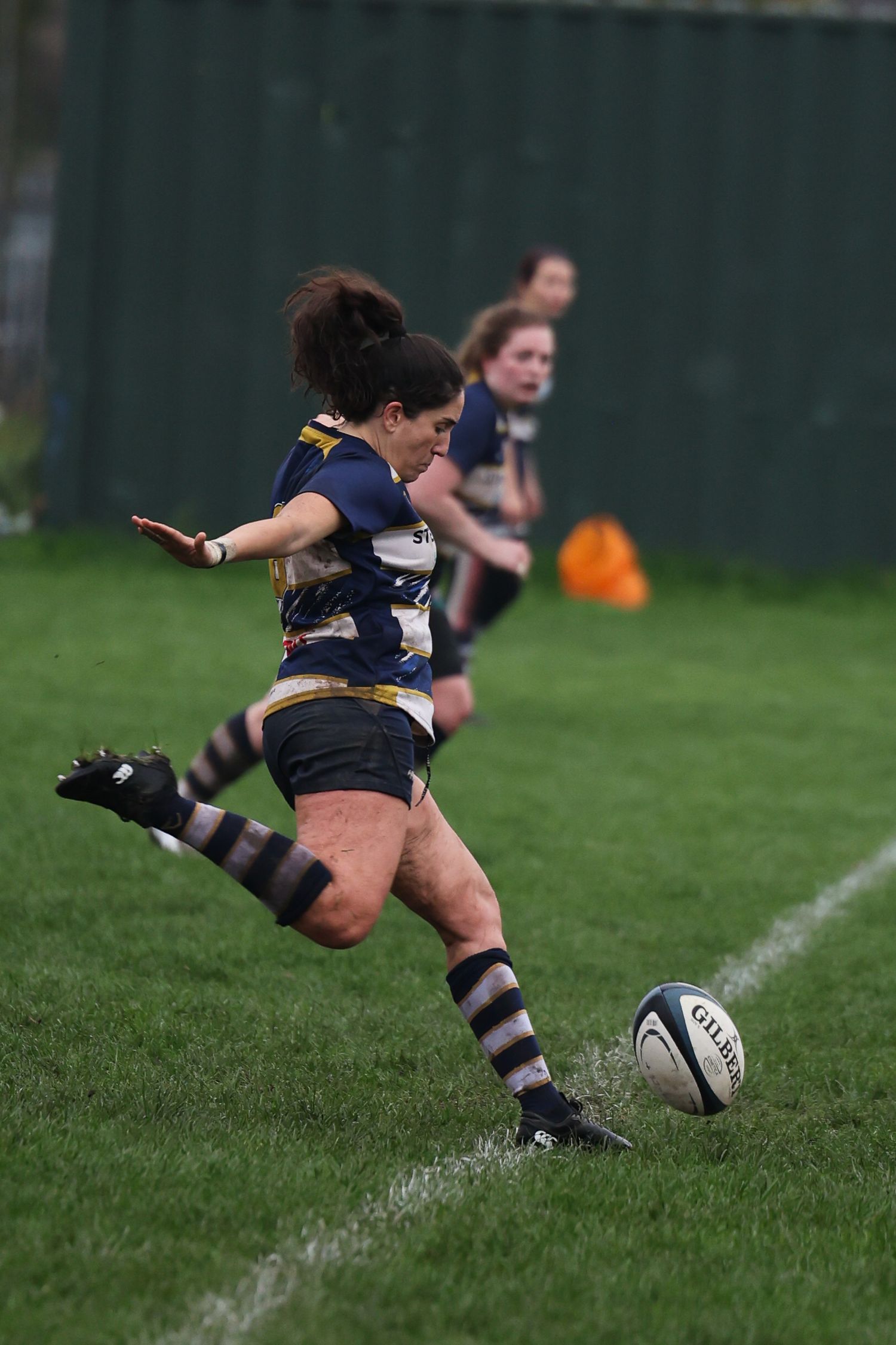 A woman in full swing kicking a ball.