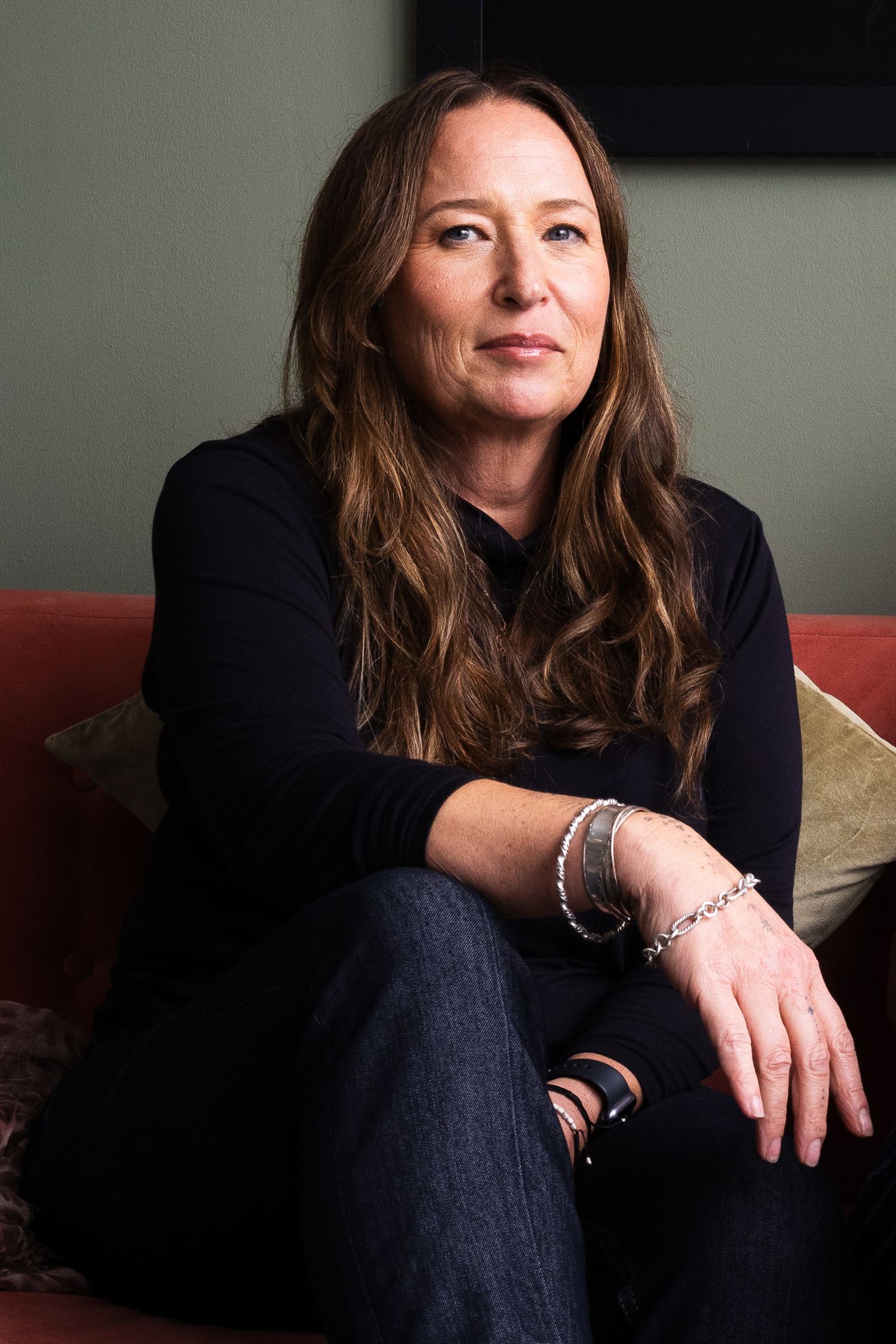 a portrait of a white woman looking at the camer with her arm leaning on her leg