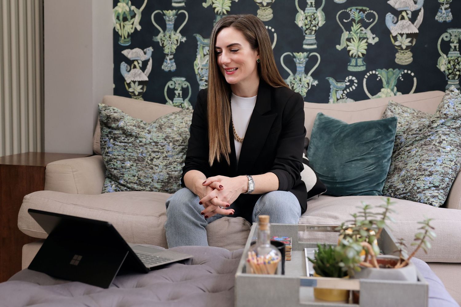 a woman casually sat on her sofa talking to her laptop with her hands crosses