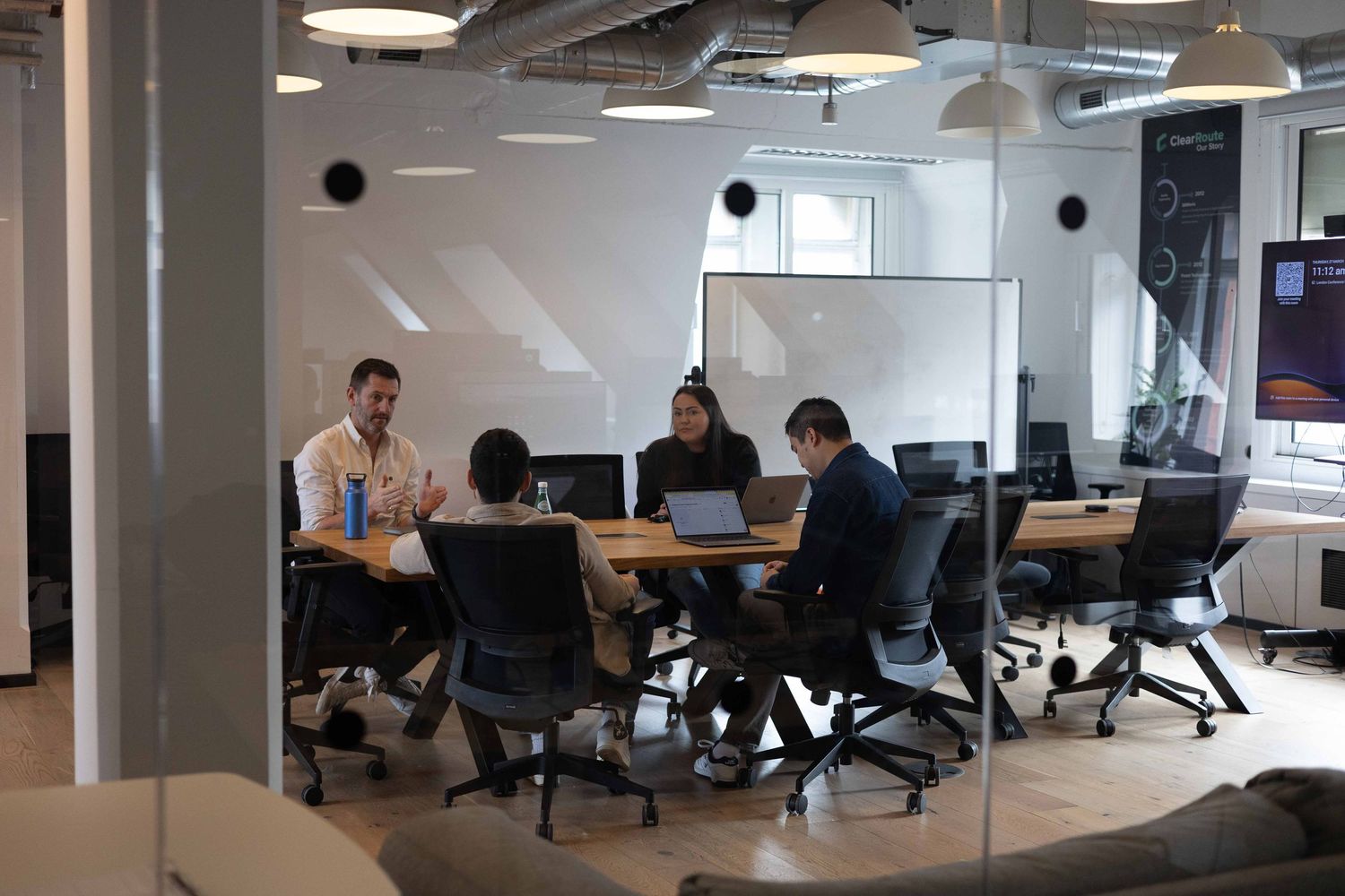 A boardroom meeting with 5 people sat around the table