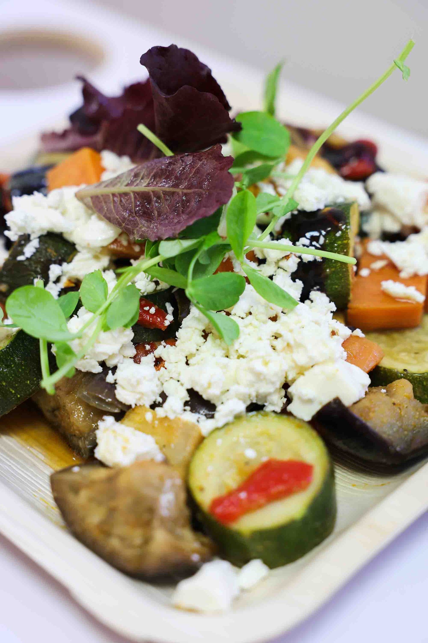 An image of vegetarian food on a plate with a flower garnish on top.