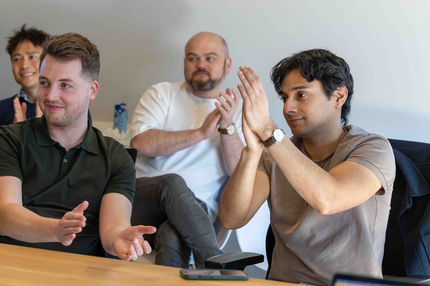 group f men sat at a casual dressed meeting where they are all clapping