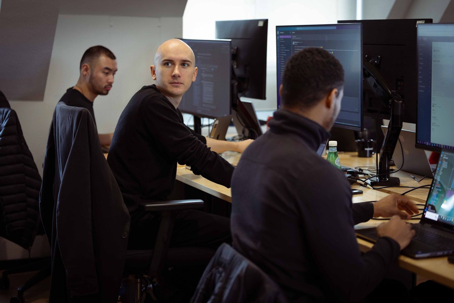 three men on computers looking up at someone talking