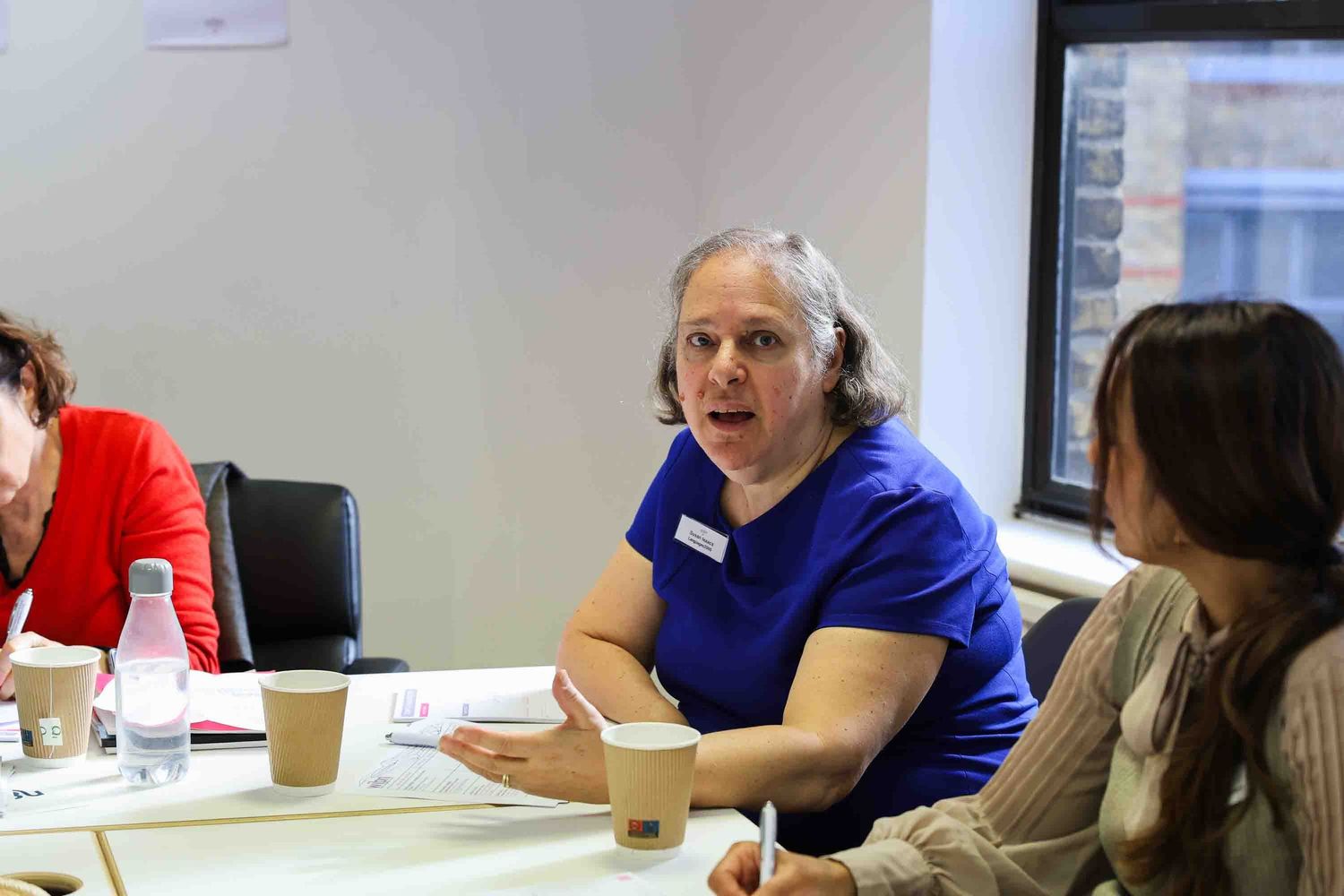 A woman in a blue top talking at a business table
