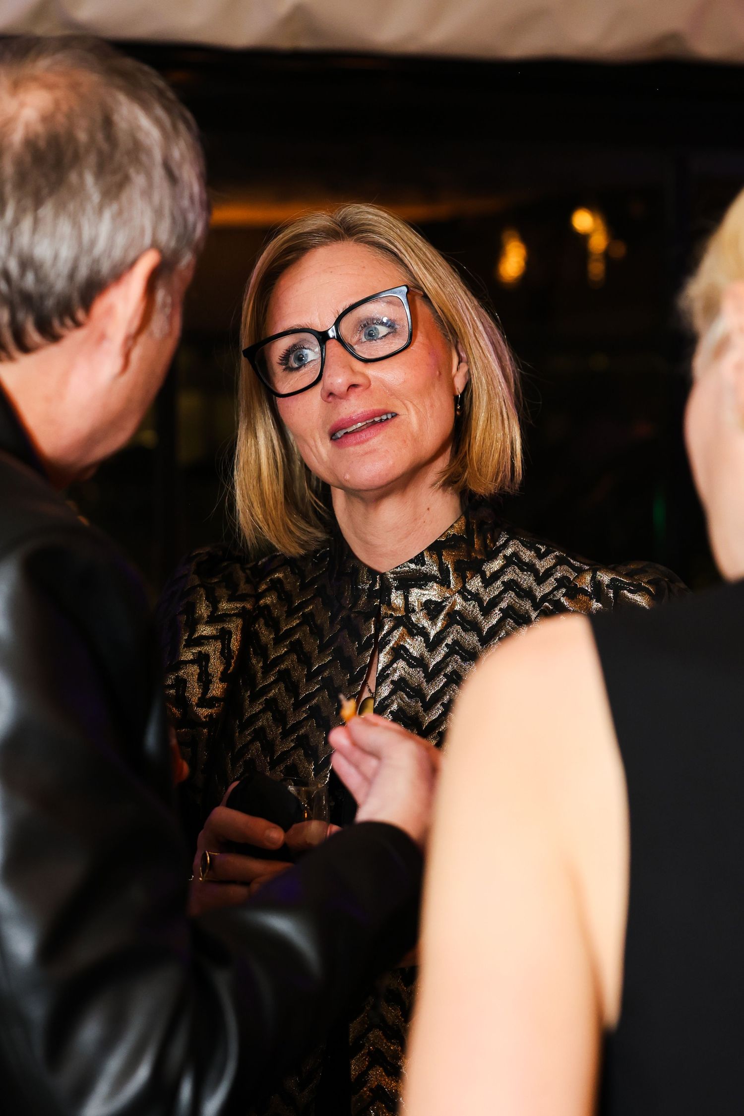 A blond women chatting to two people at an a event