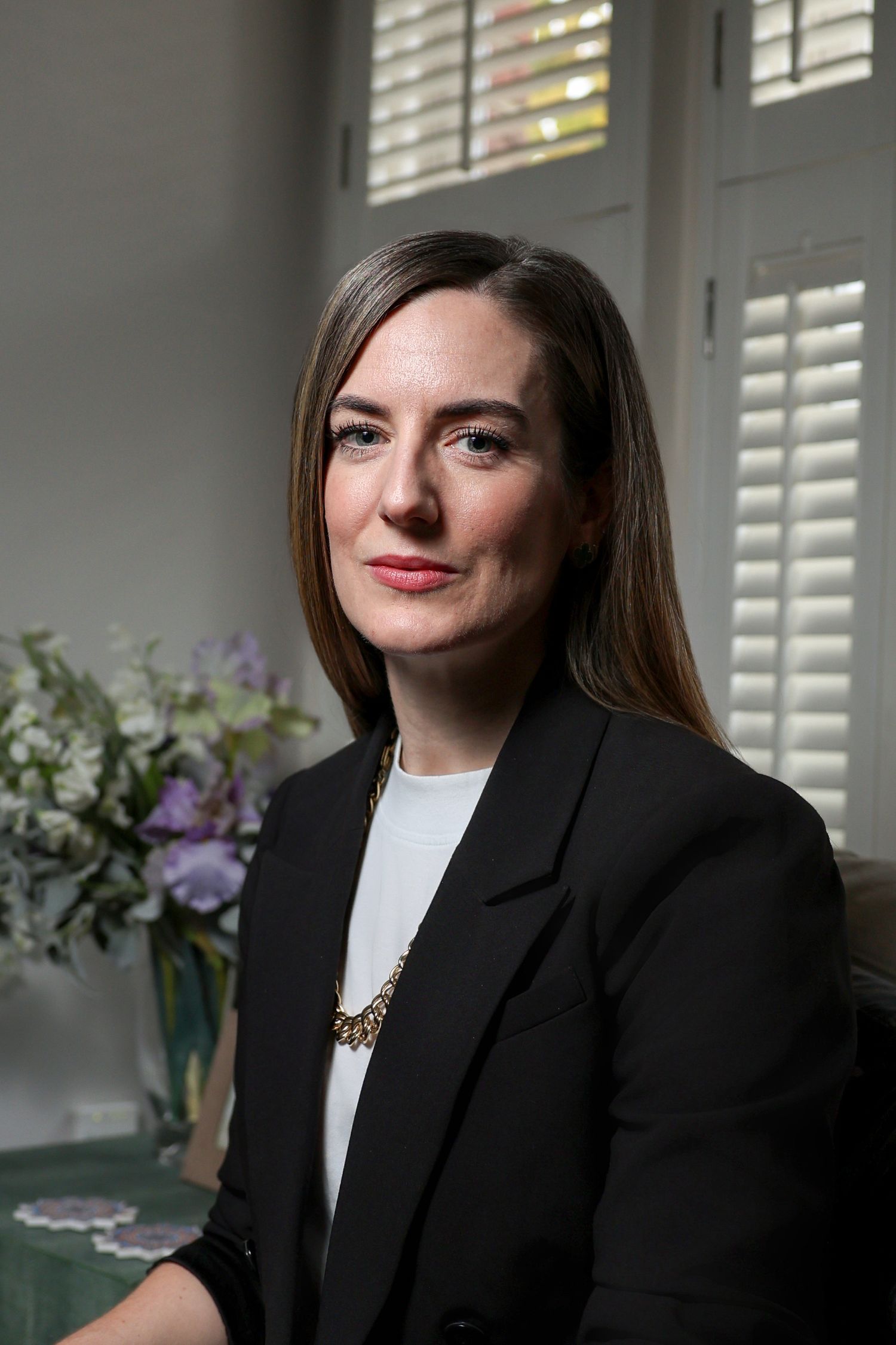 a portrait of a woman in a dark suit jacket sat on her sofa