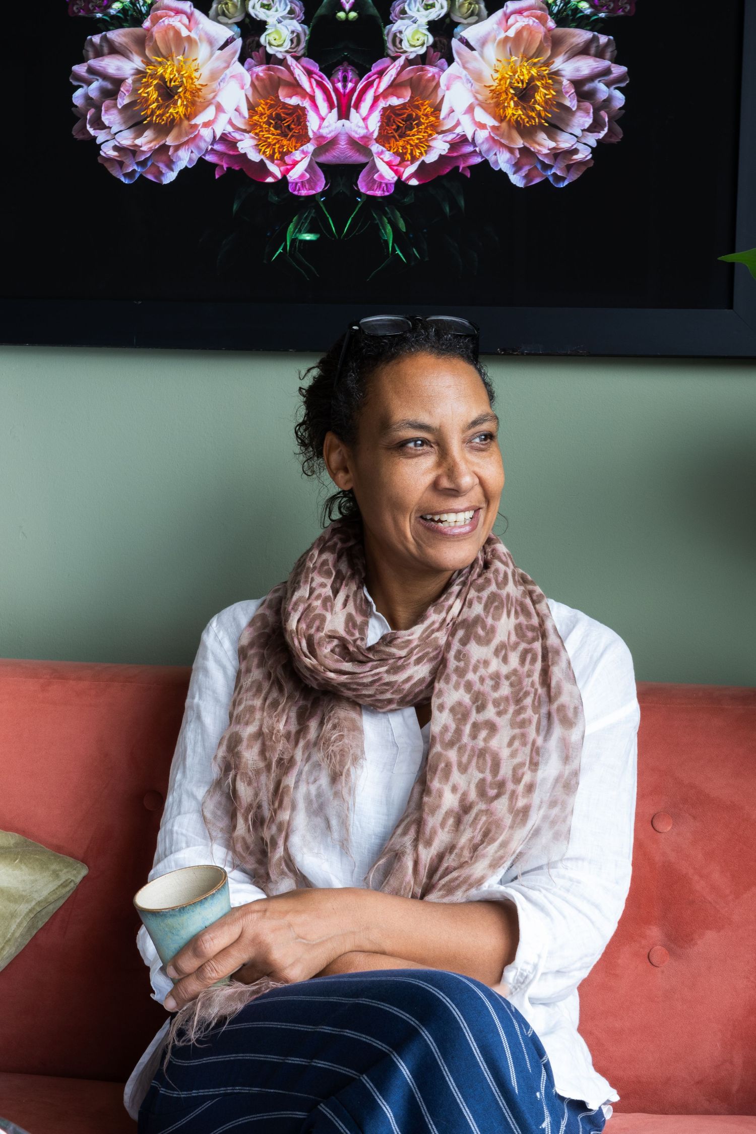 A black woman relaxed and sat in a white top on an orange sofa looking to the right