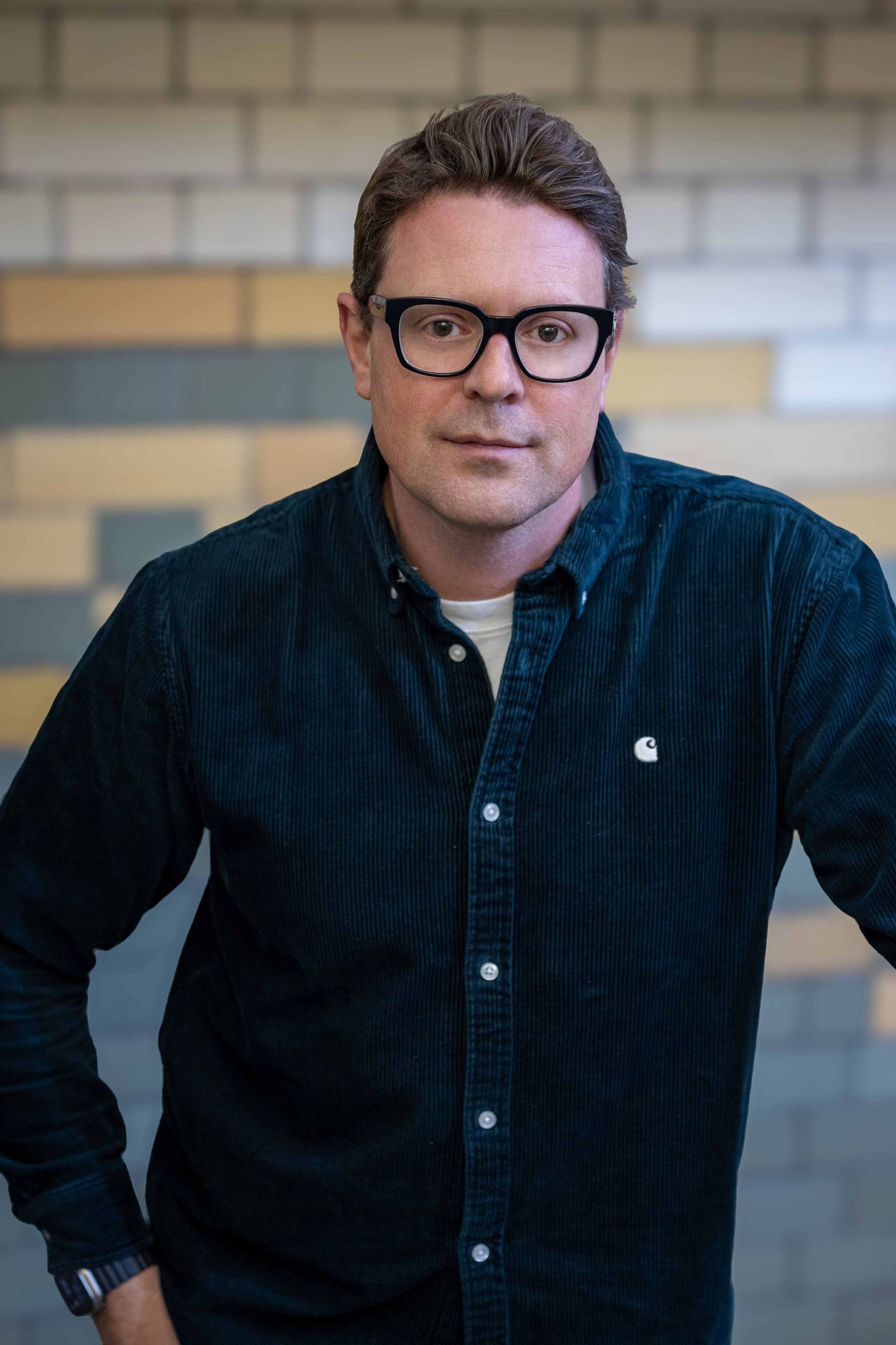 man in a stair well looking at the camera wearing glassses and a green shirt