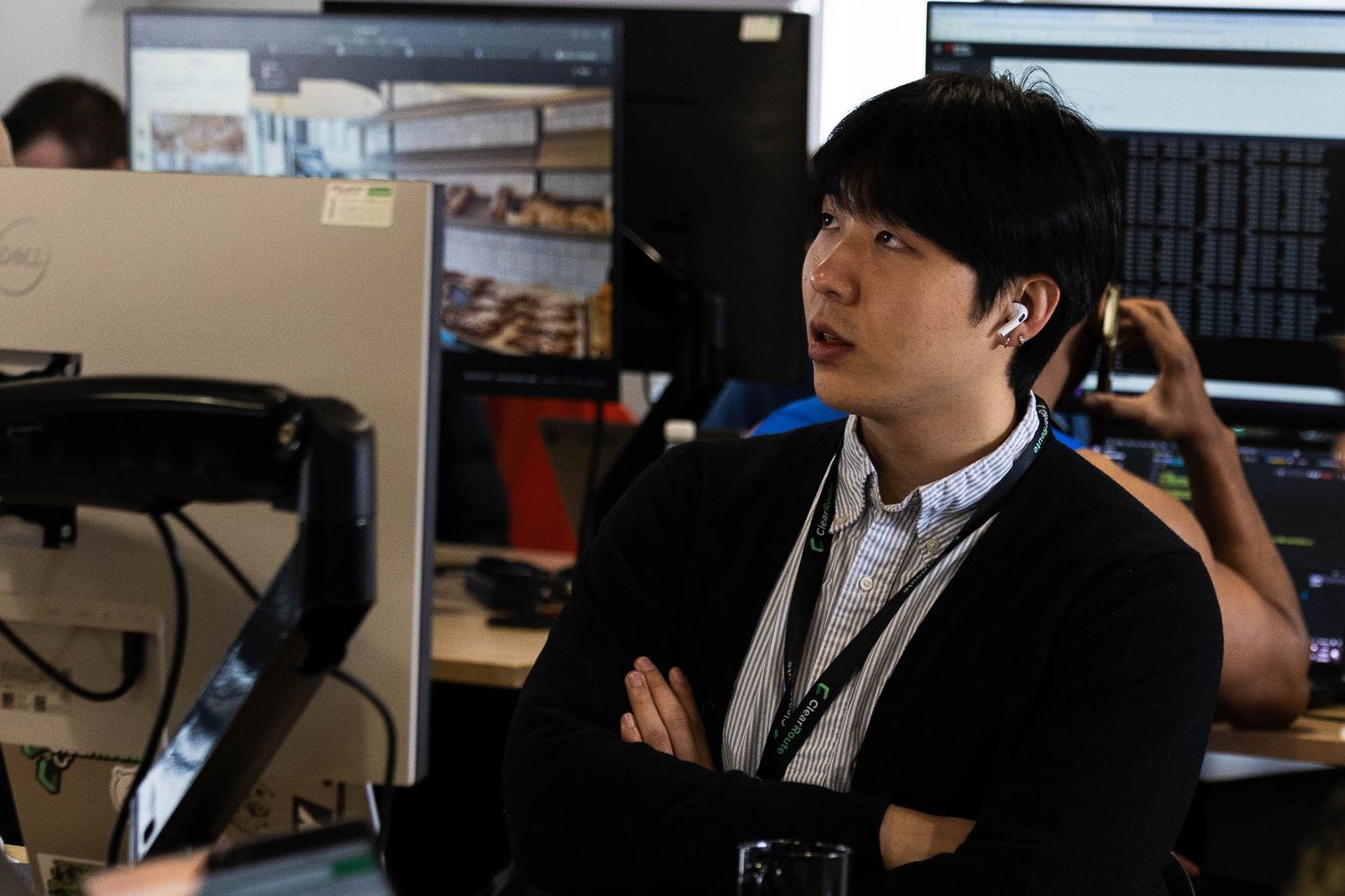 Asian man is sat crossed arms looking at his computer