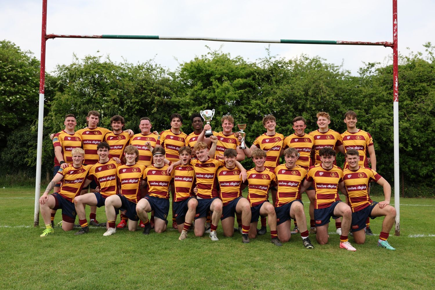 Winning team picture under the rugby posts holding the trophy