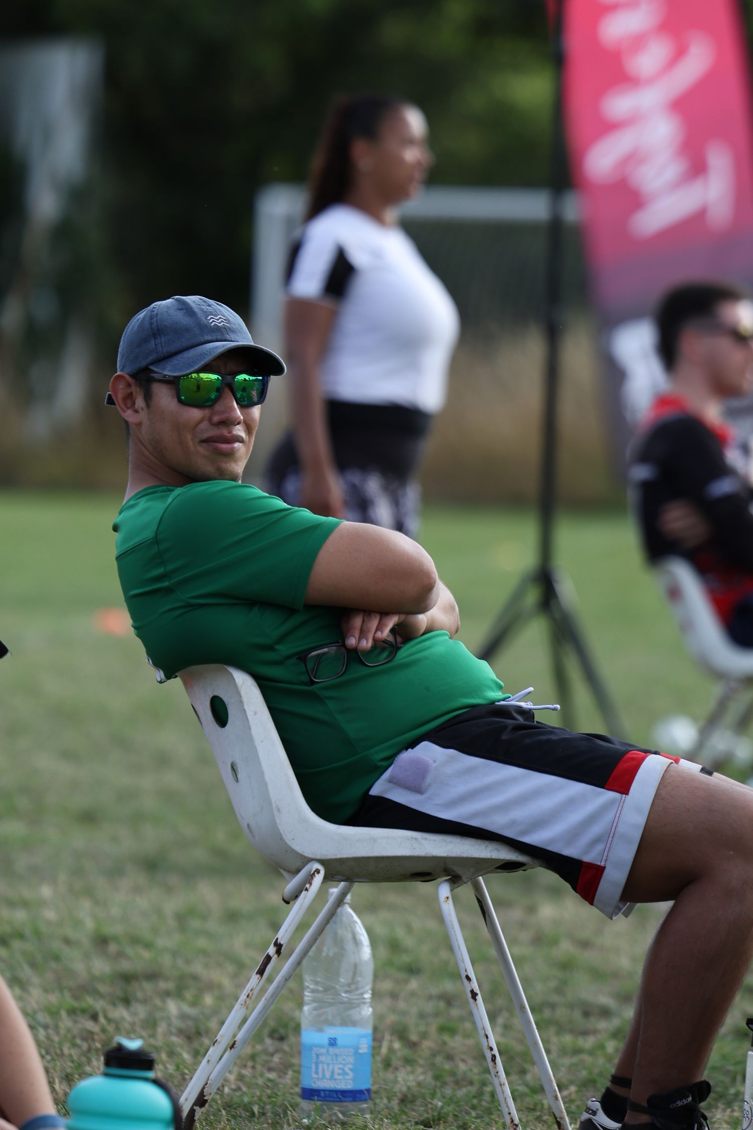man in green shirt and hat sat watching tag rugby games
