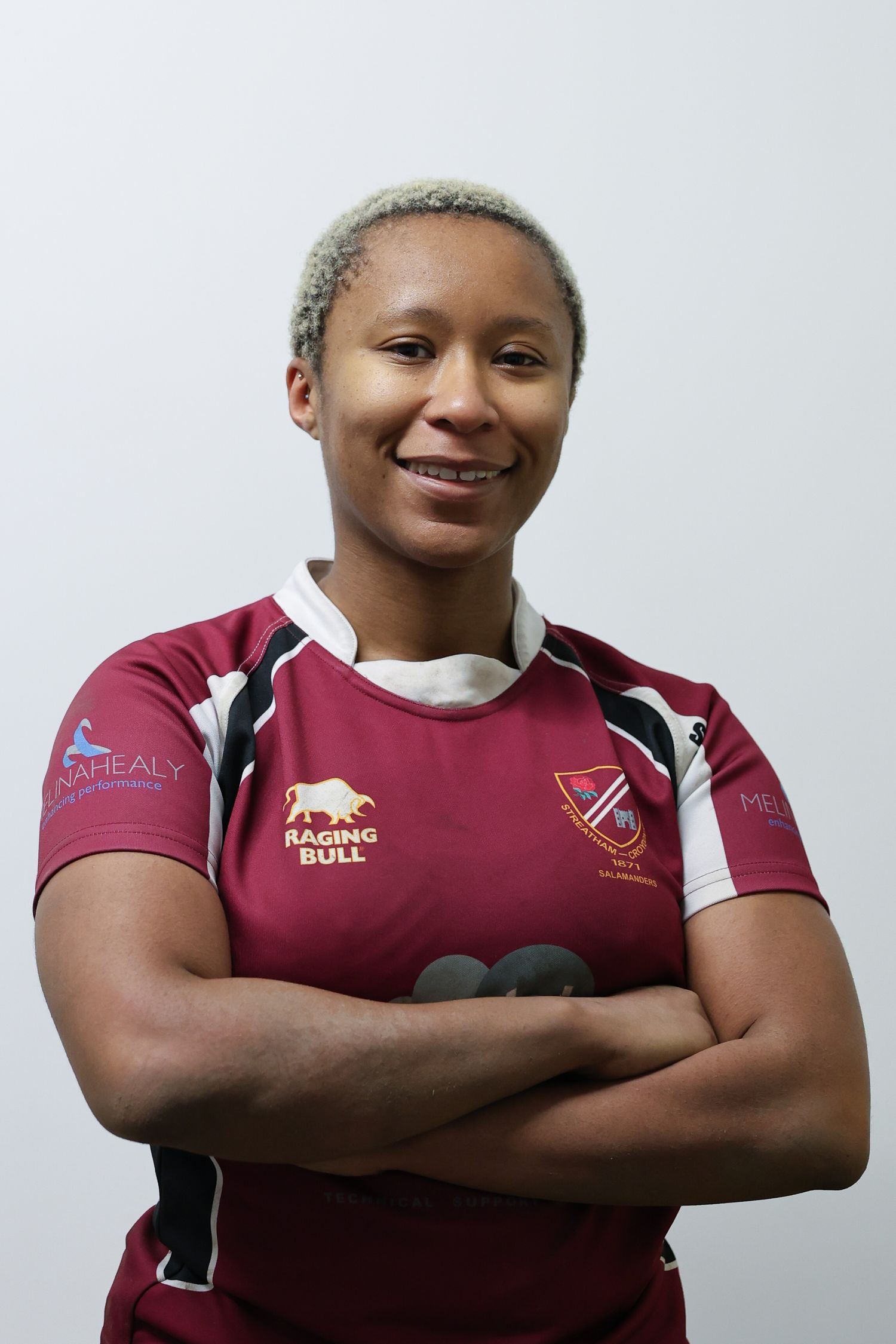 Portrait of a black woman with short bleached hair standing with her arms crossed