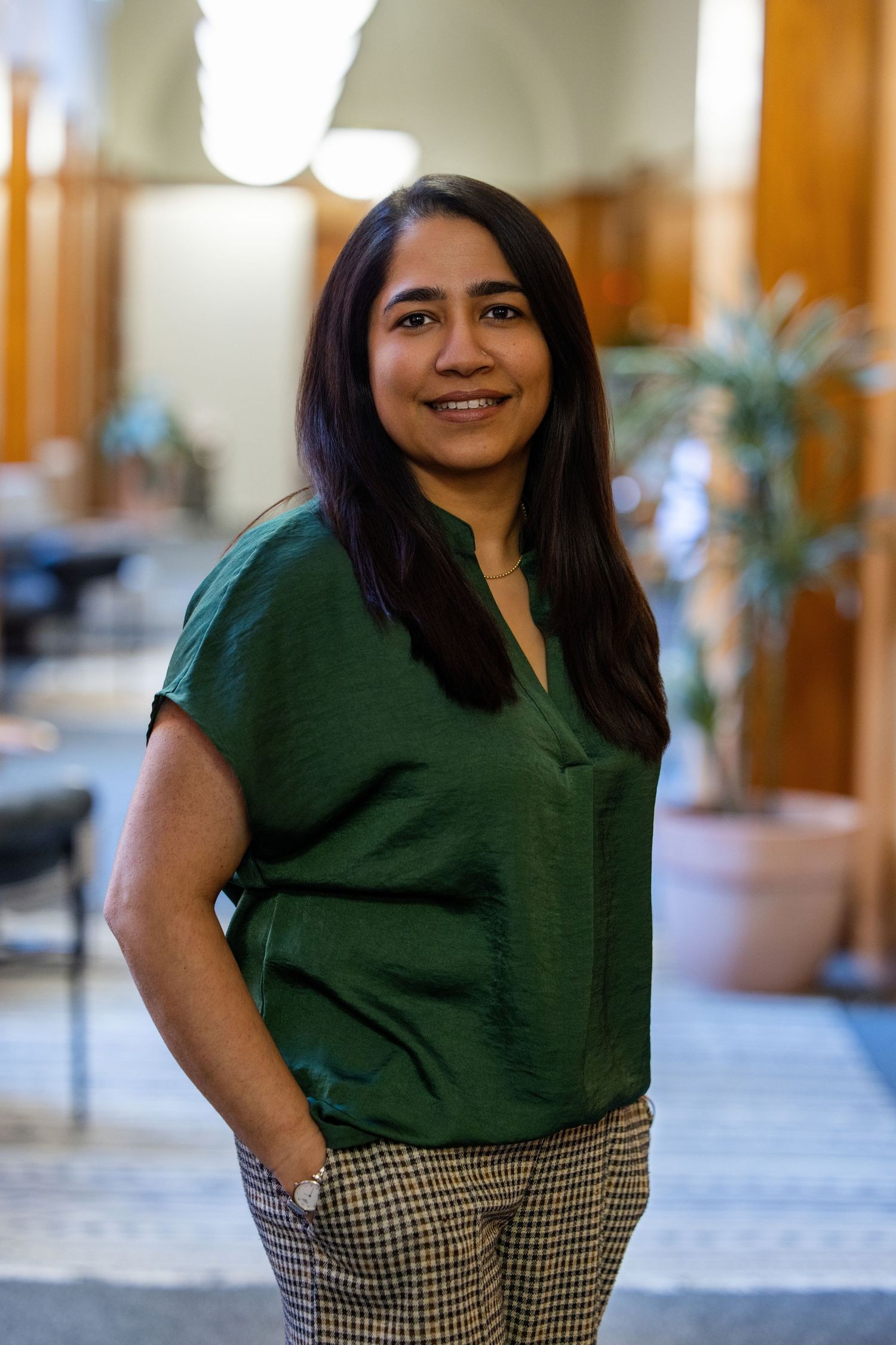 A Asian woman wearing a green top with an office behind her