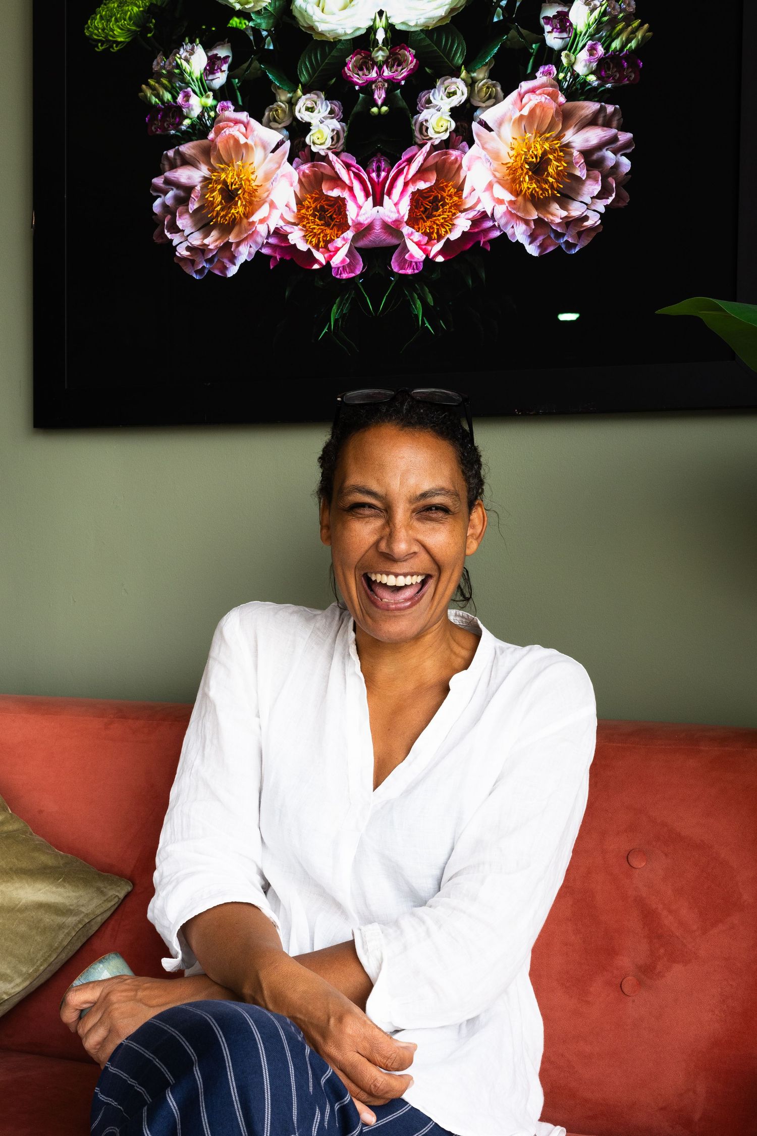 a black woman relaxed and sat in a white top on an orange sofa laughing