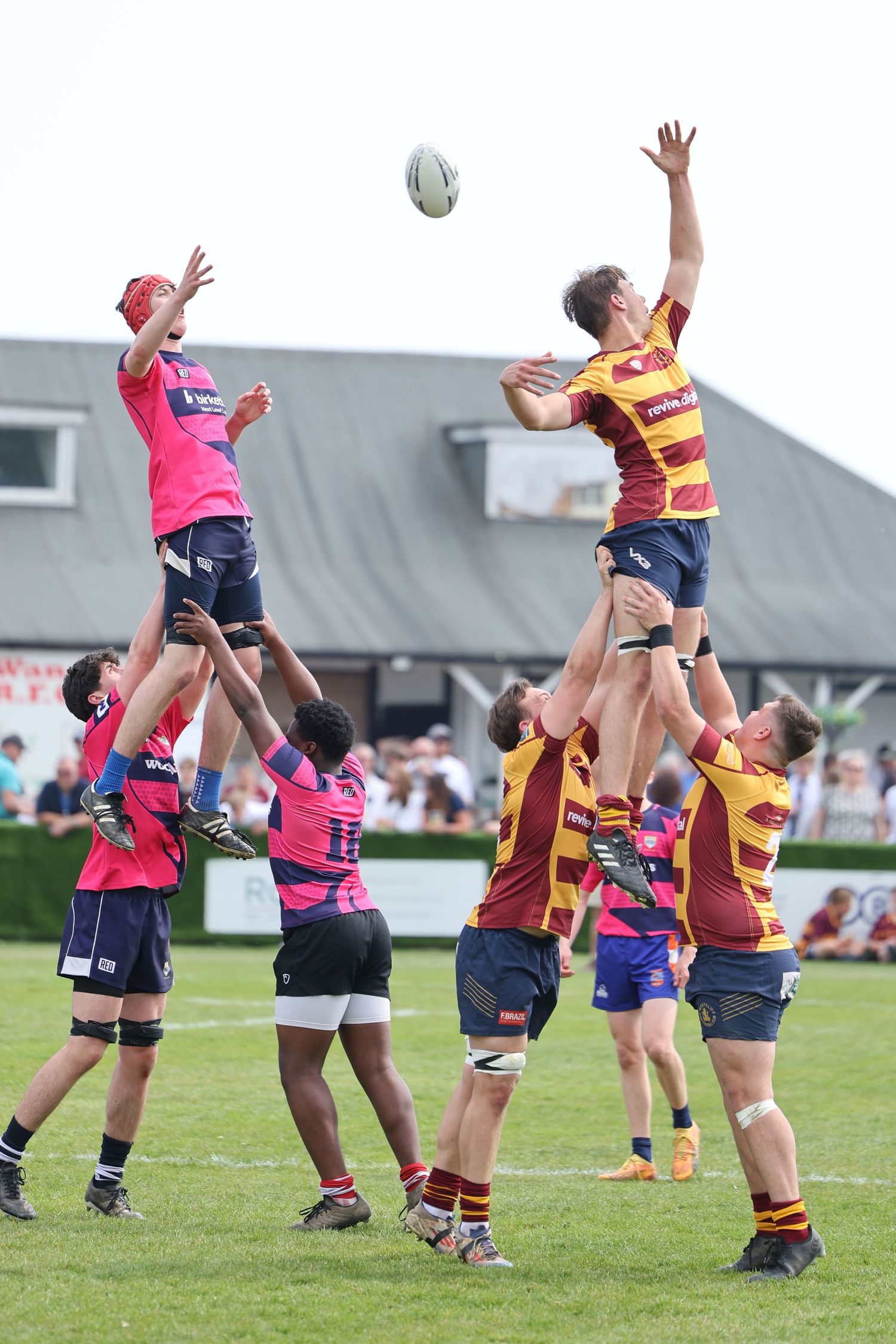 Two teams are doing a line out where they jump into the air to catch the ball being thrown in