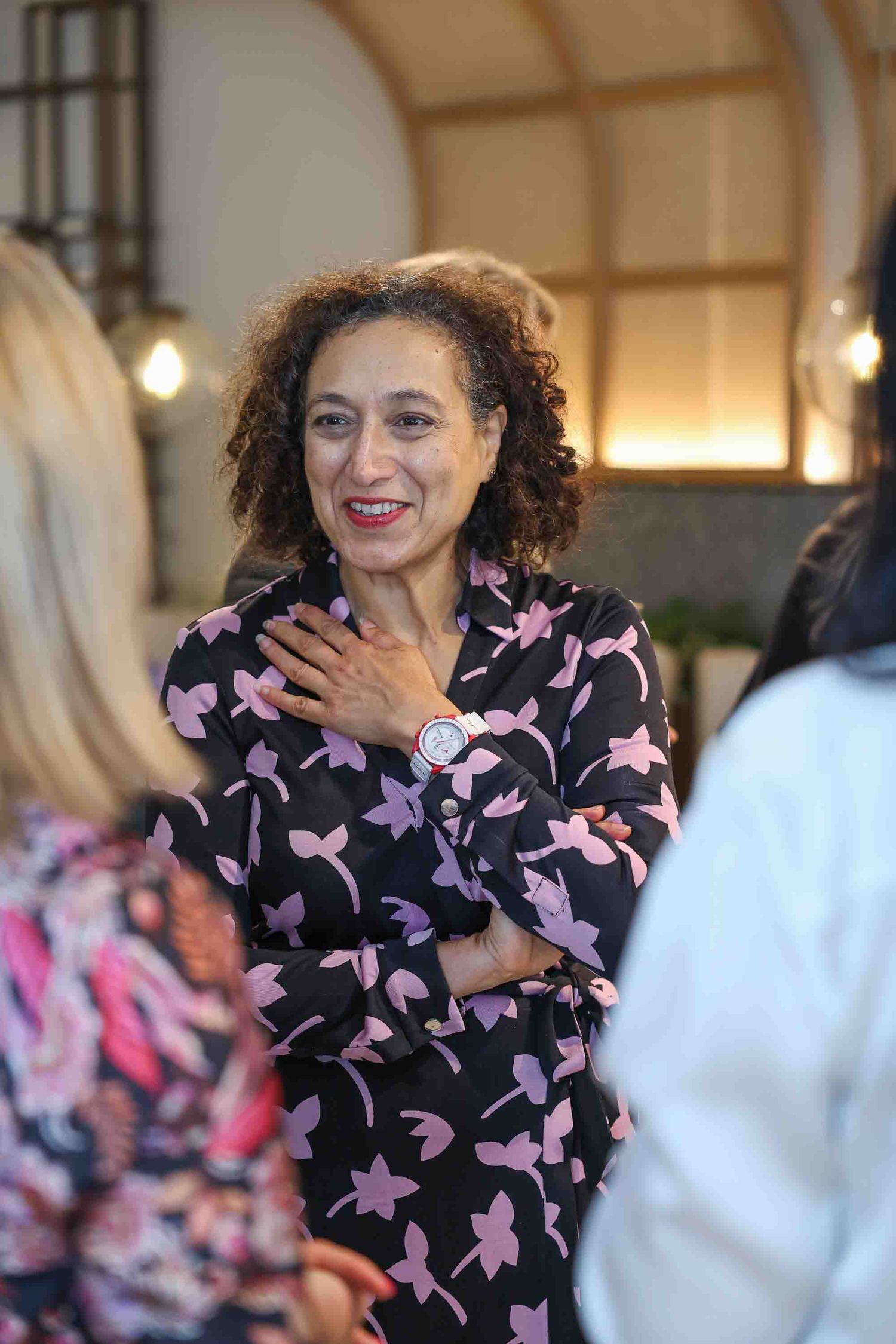 A woman in a floral dress smiling in a crowded business network meeting