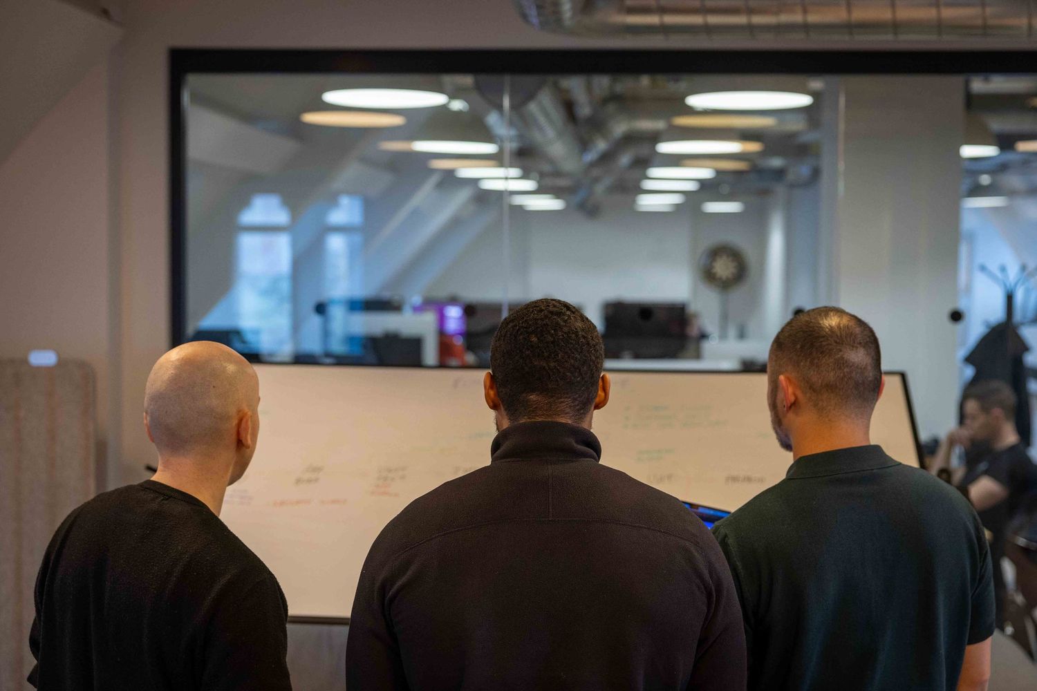 3 men look at at large white board
