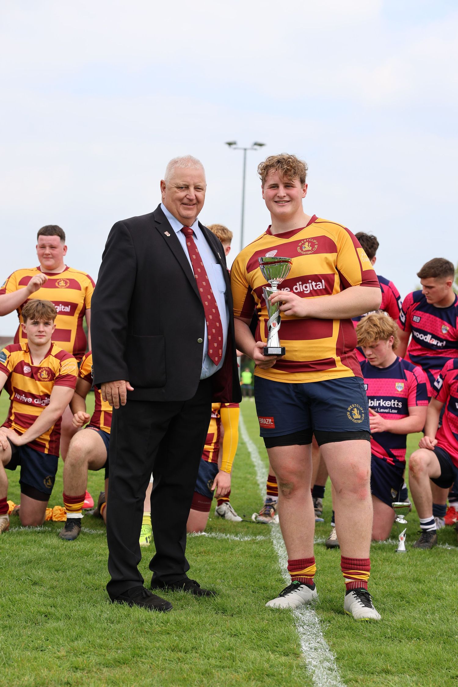 captain getting the trophy from a man in a suit.