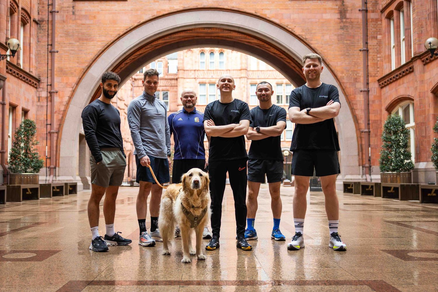 a group of runners and their dog standing under a arch ready for a run