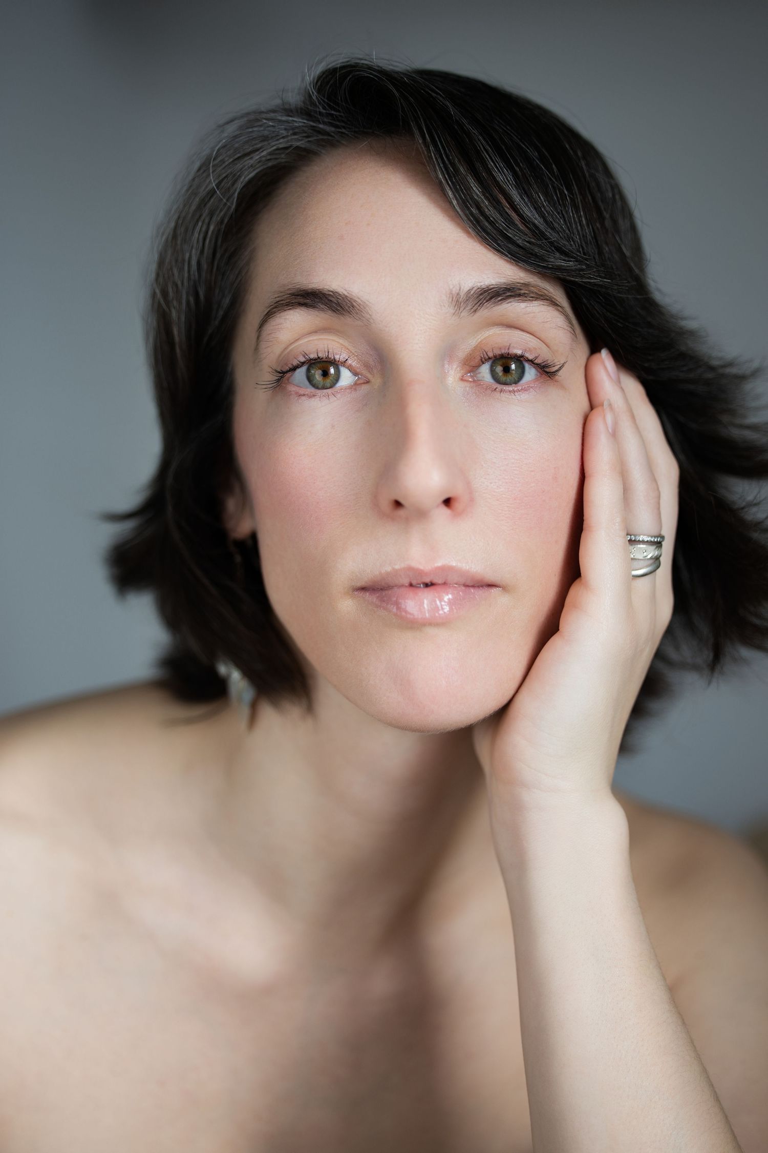 A close p of a white woman looking at the camera with her hands on her face