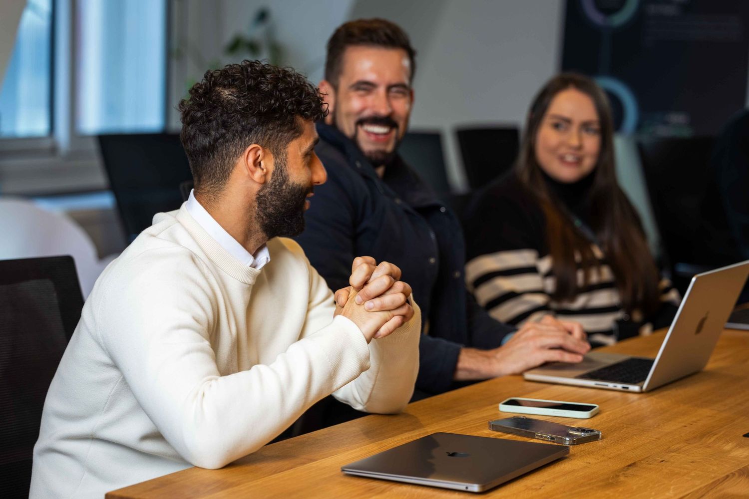 3 people laughing together at a board room meeting
