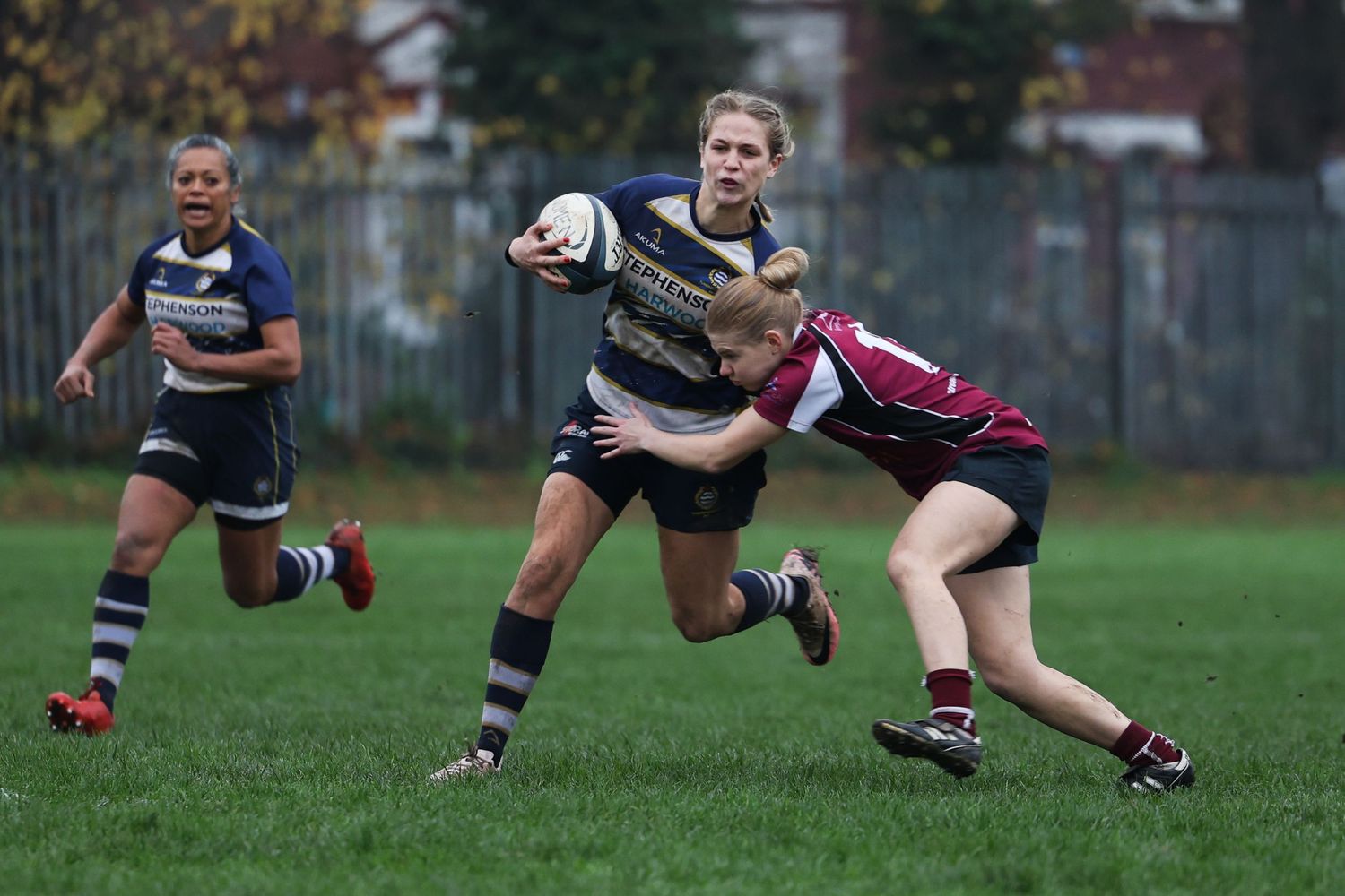A woman being tackled by her opponent in a woman's rugby game