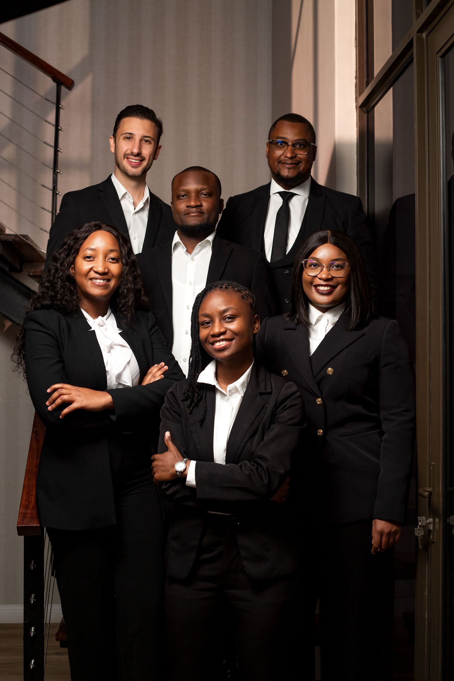 Corporate team photo featuring diverse professionals in formal black and white attire.