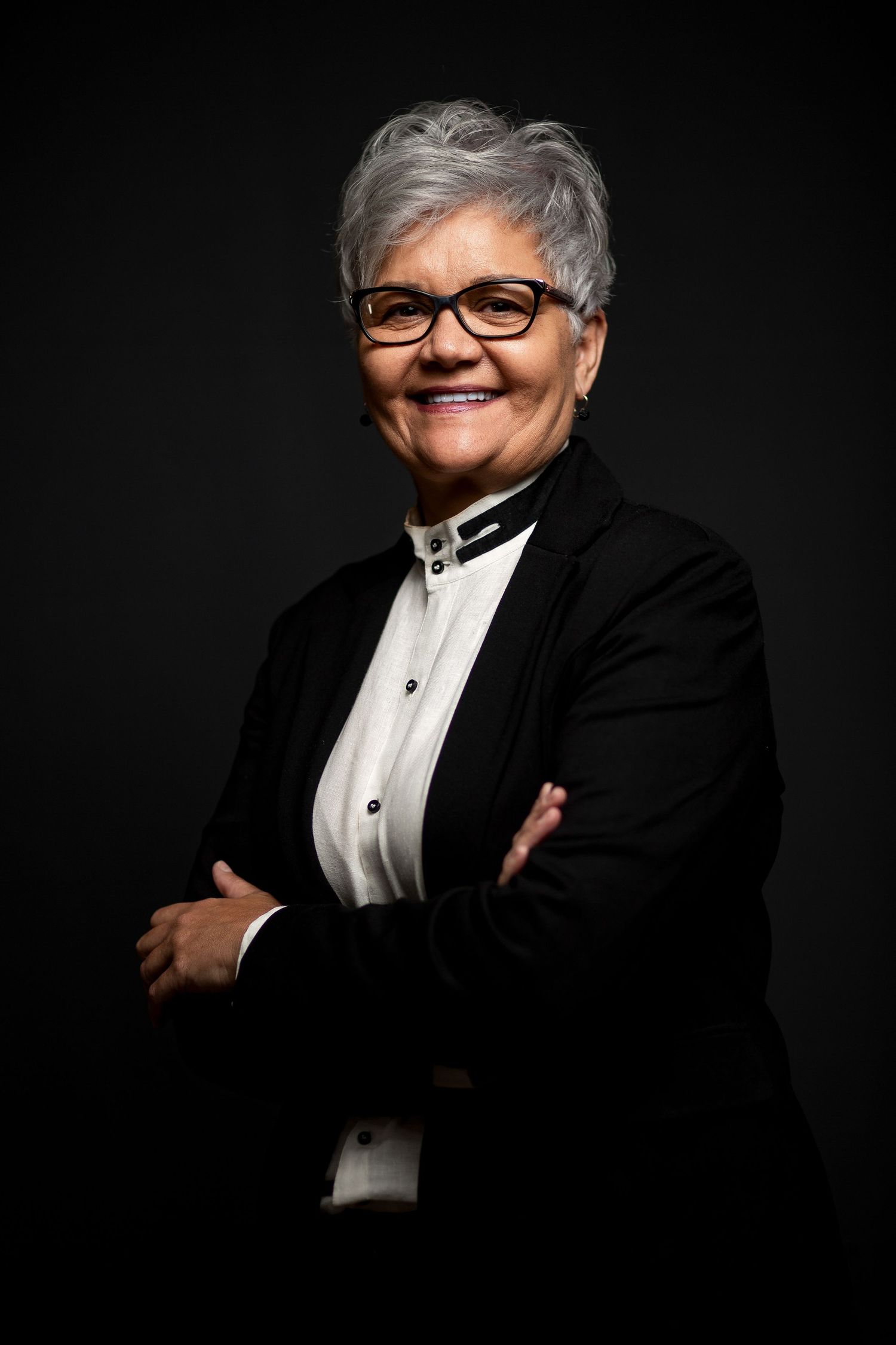 Professional headshots of a person in formal black and white attire against dark background.