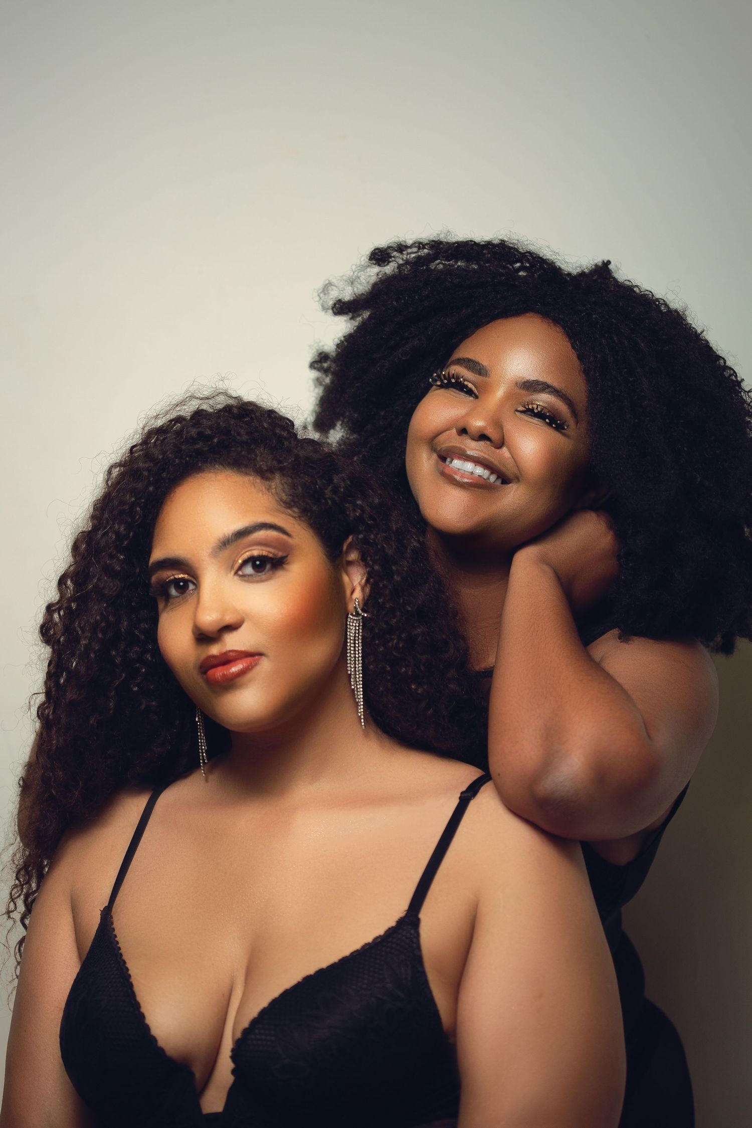 Intimate studio portrait session with models in black lingerie against neutral backdrop.