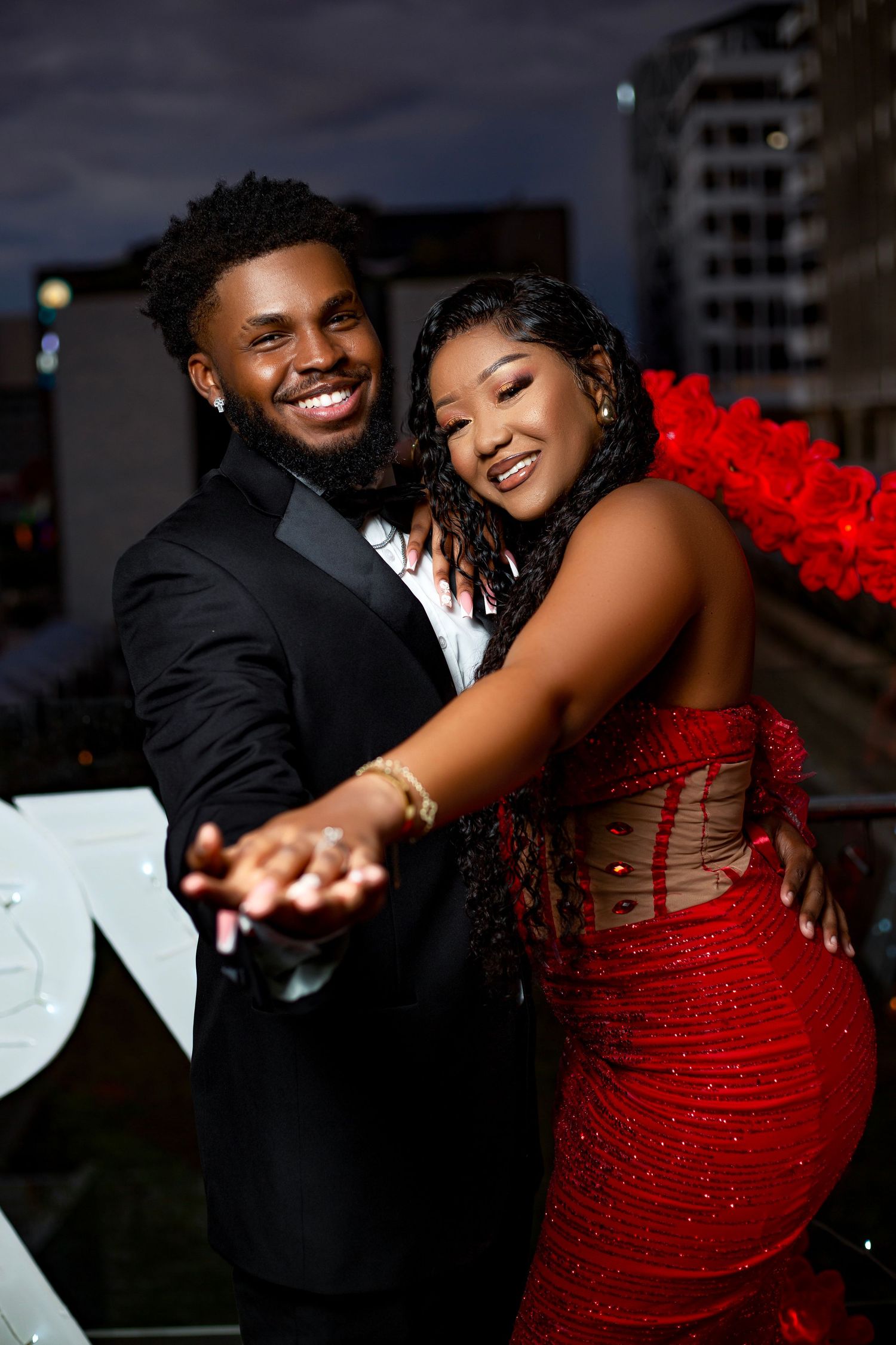A couple shares intimate dance moments in an urban setting, with the woman wearing a sparkly red dress.