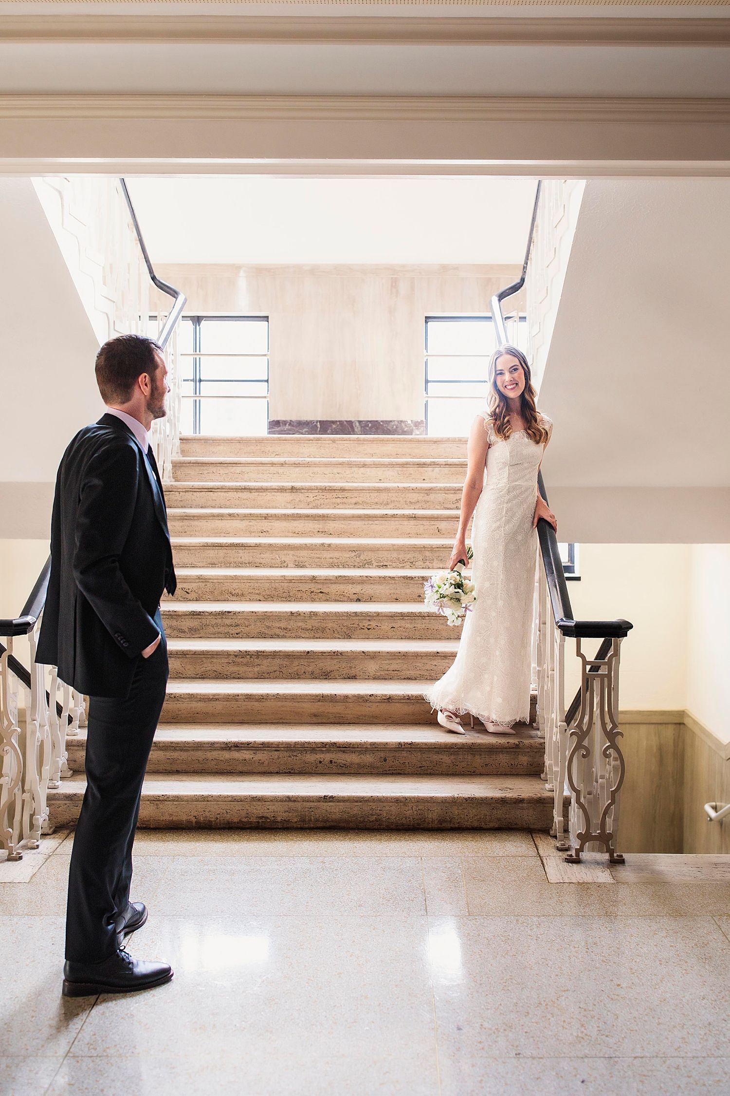 newlyweds smile at each other on stairs after courthouse ceremony