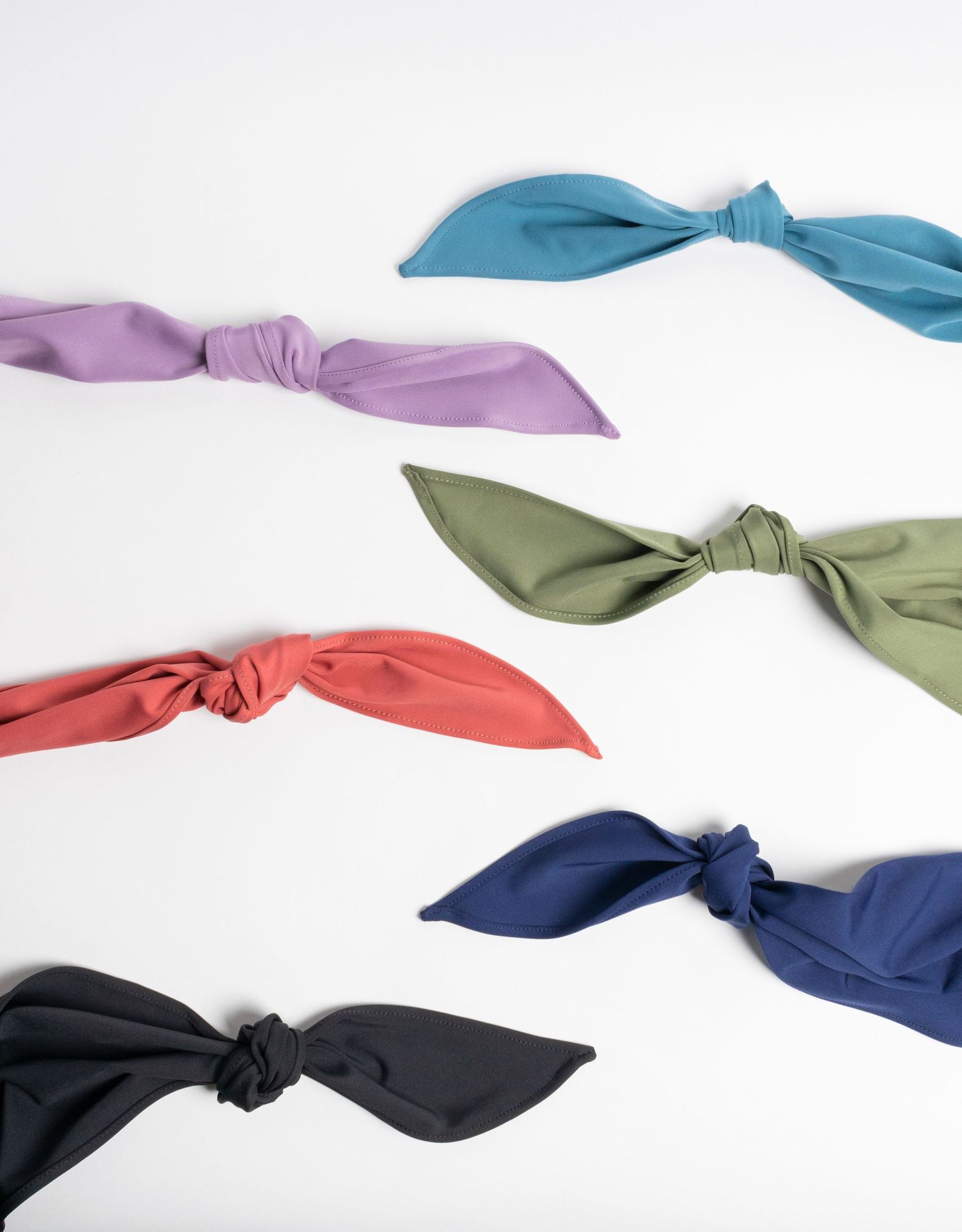 Flat lay product photography of various colored knotted fabrics on a white background.