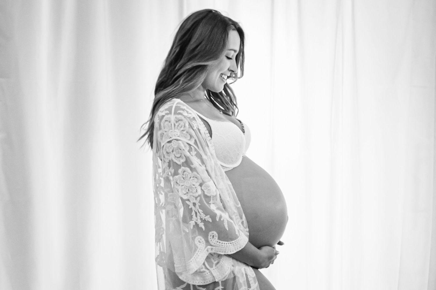 black and white maternity photo, mom is holding belly smiling