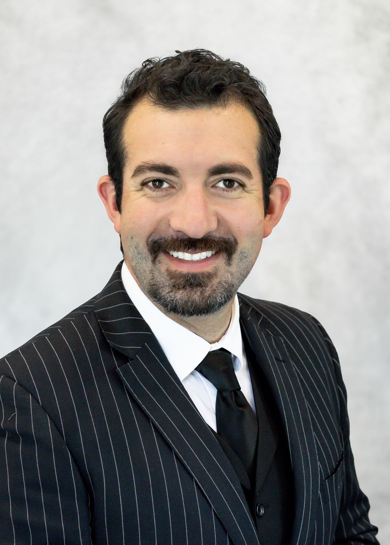 Professional headshot series of a man in pinstripe suit and black tie against white background.