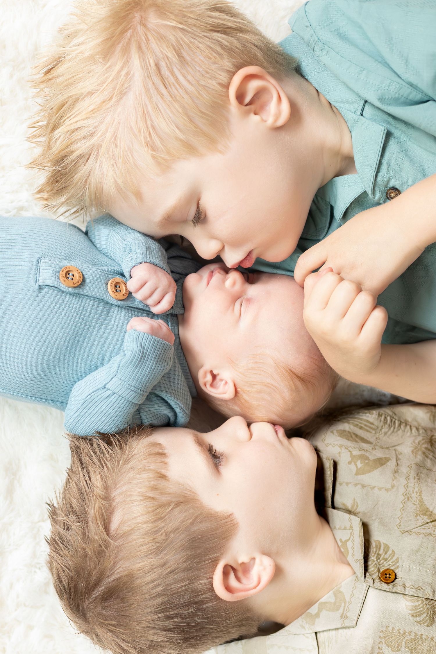 Two siblings share a tender moment lying down together in matching blue outfits.