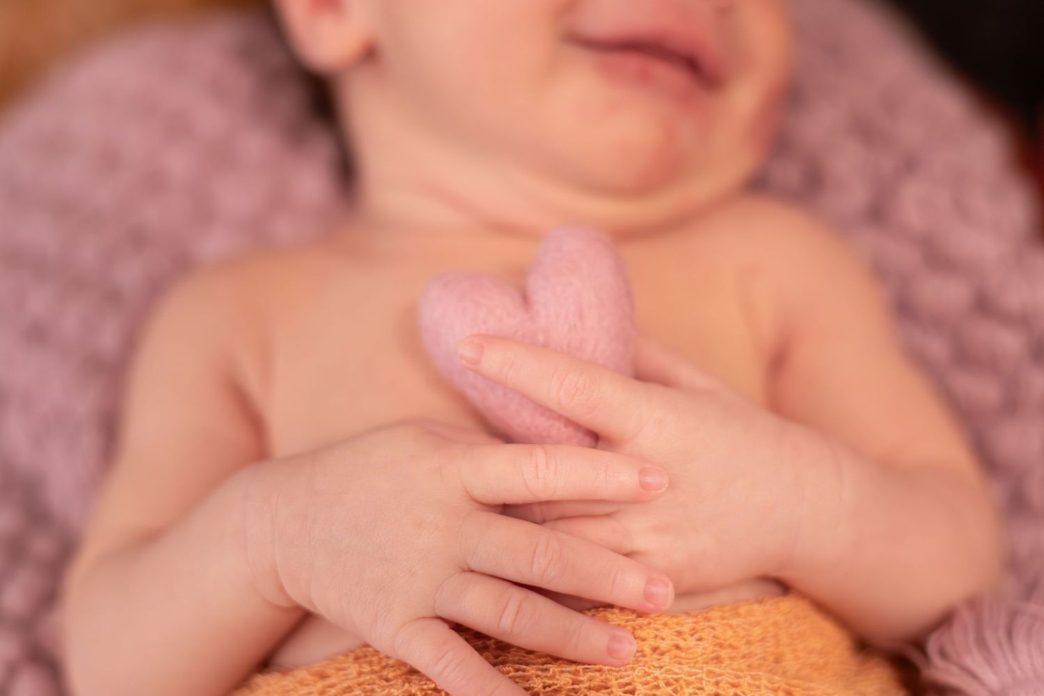 A series of closeup photos showing a baby wearing an orange knit outfit during a newborn photography session.